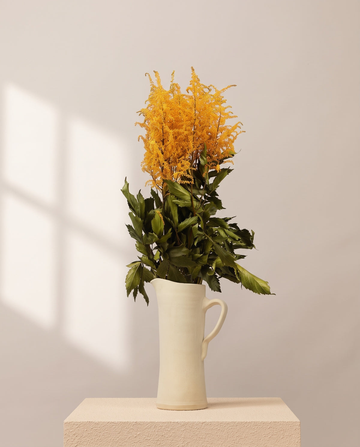 Astilbe preservada amarela numa jarra de cerâmica creme. Jarra não incluída.