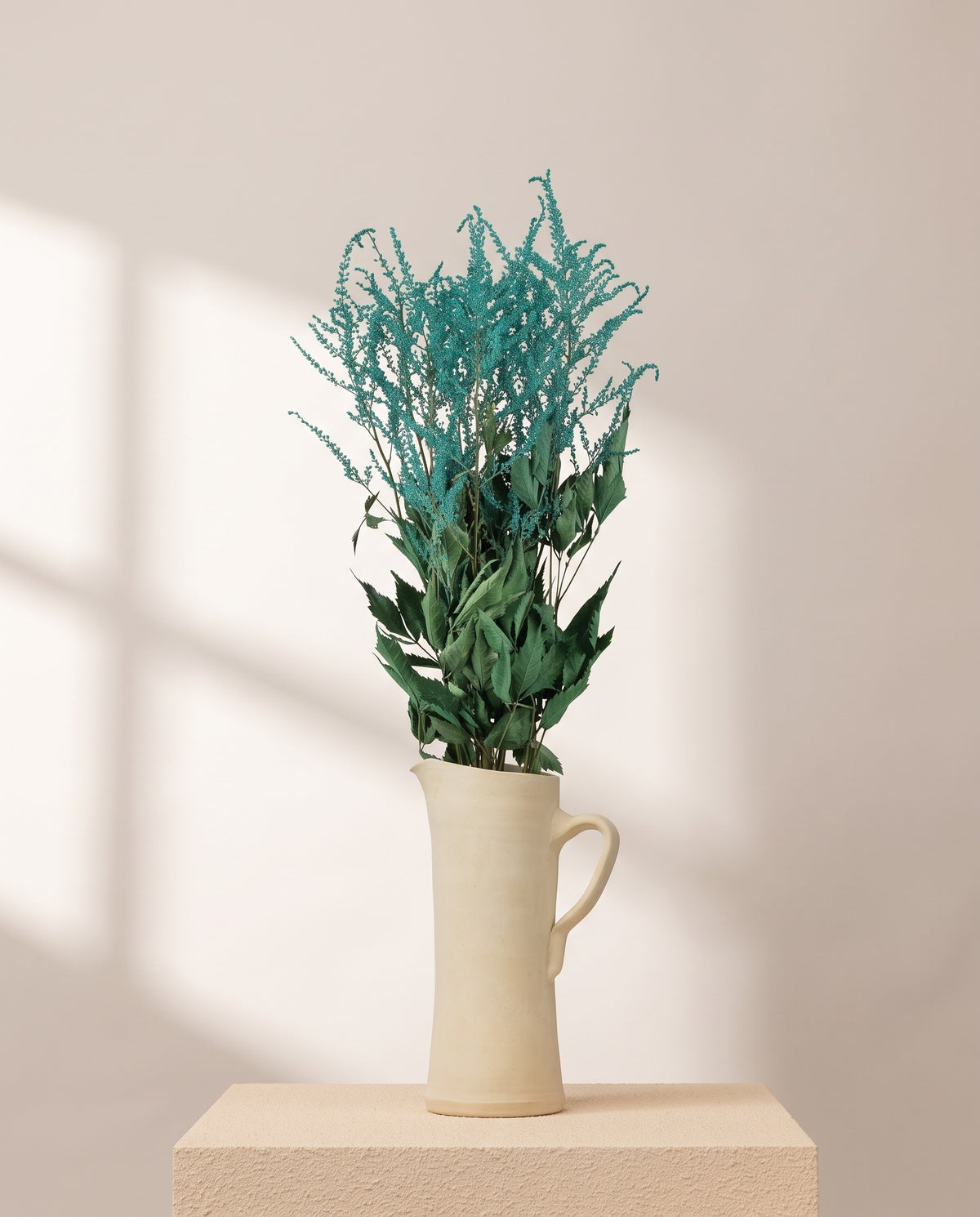 Astilbe preservada turquesa numa jarra de cerâmica creme. Jarra não incluída.