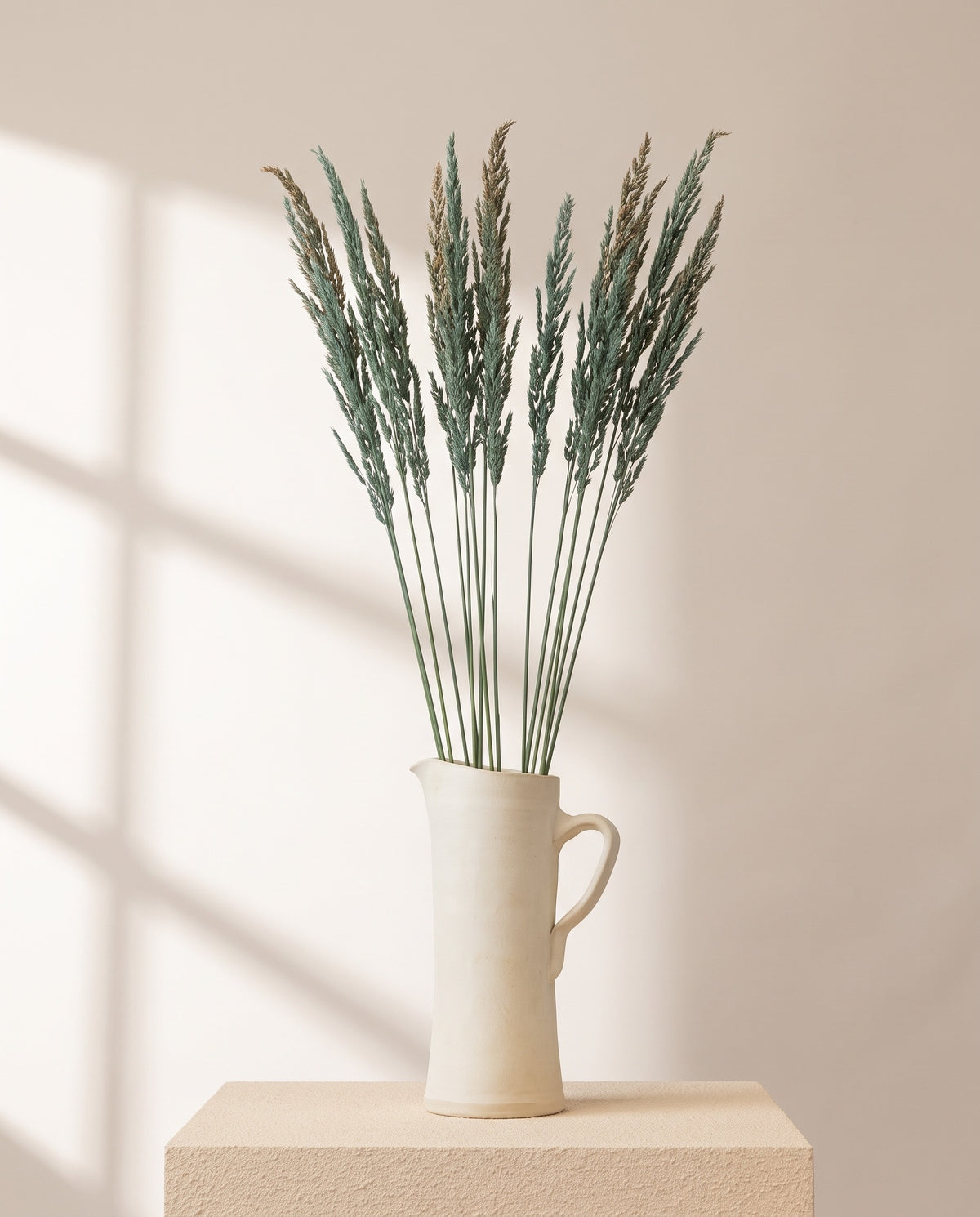 Calamagrostis preservada azul en una jarra de cerámica crema, ambientada. Jarra no incluida.