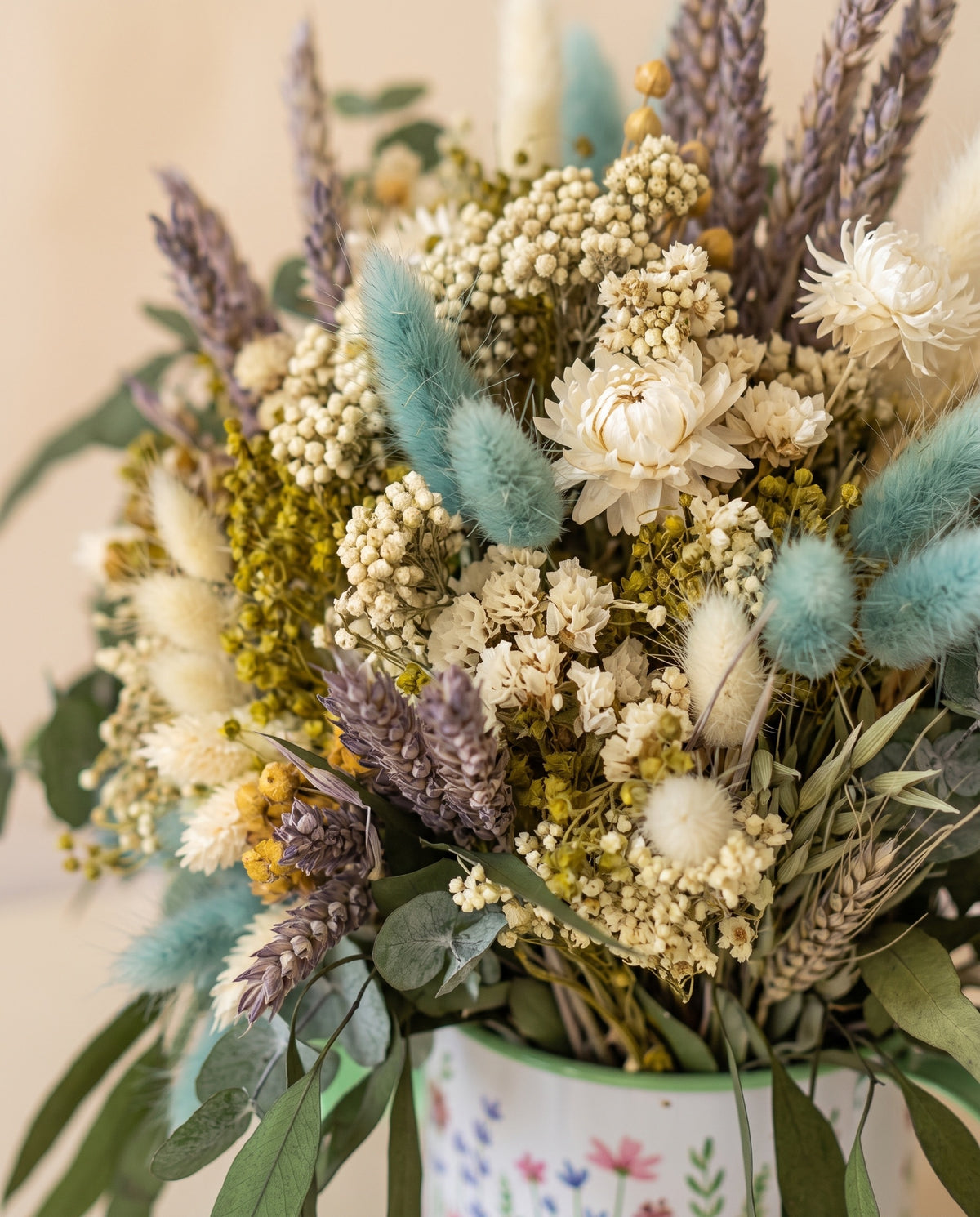 Detalle de cerca del centro de flores secas y preservadas en azul y crema.