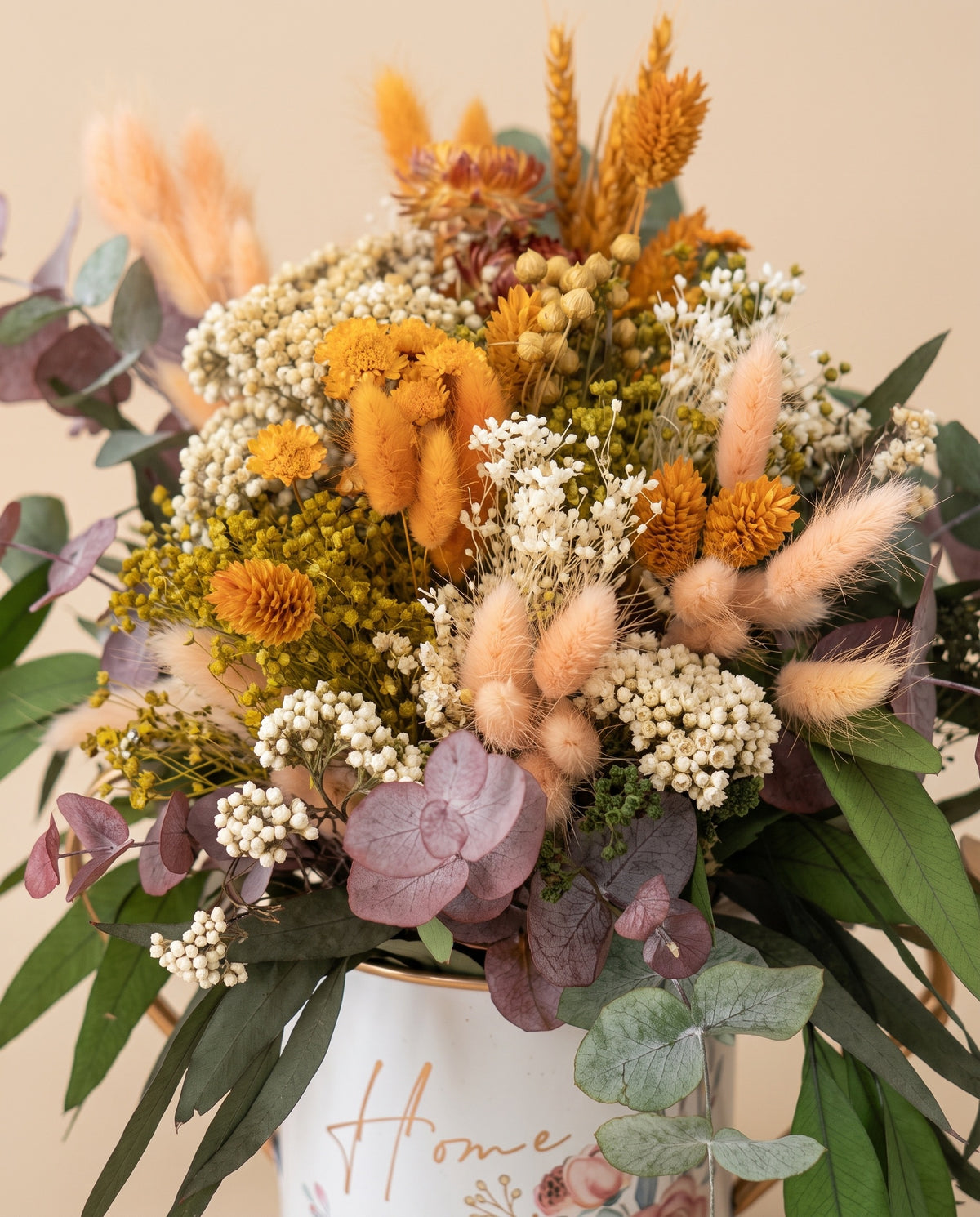 Detalle de cerca del centro de flores secas y preservadas en naranja y crema.