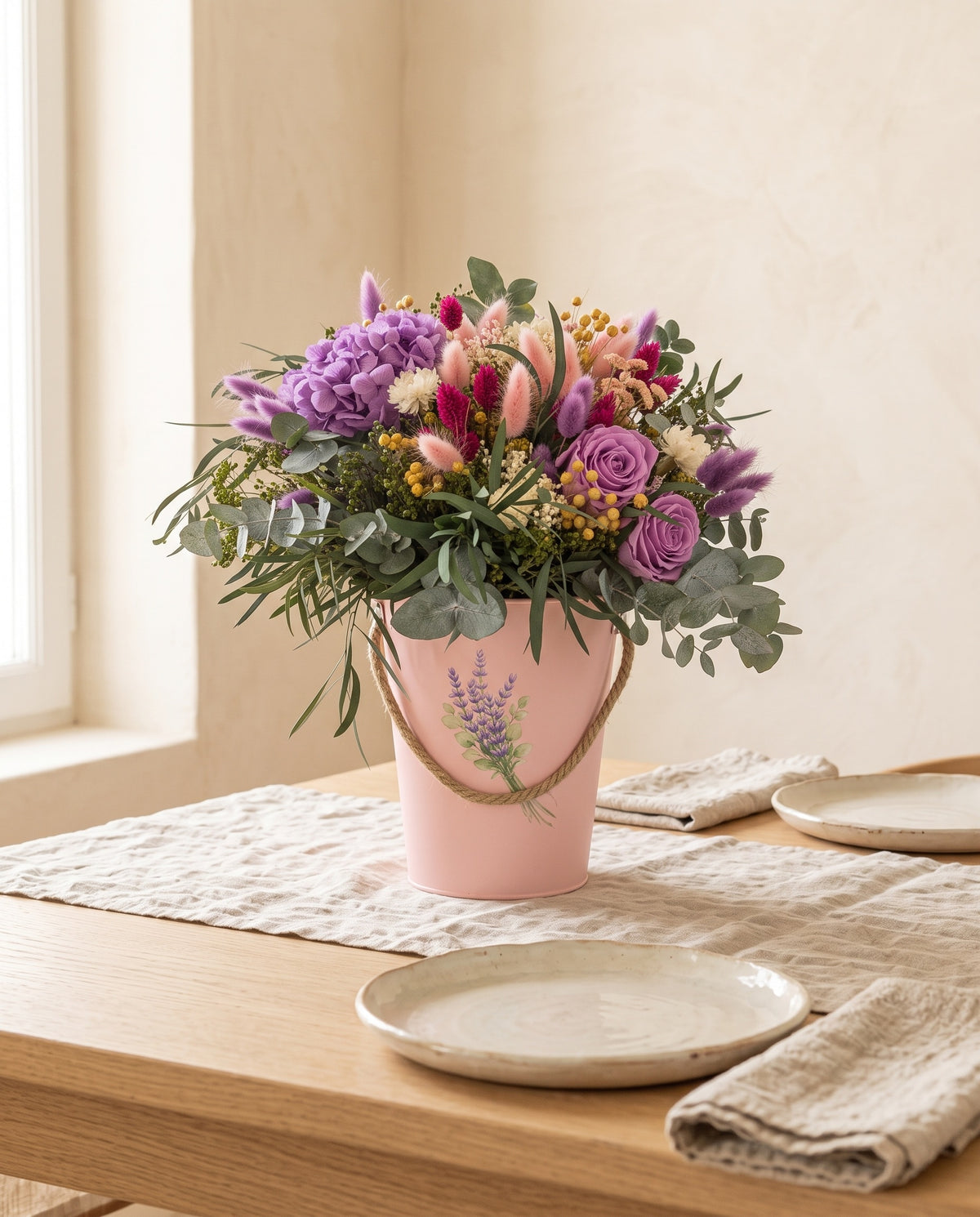 Centro de flores secas y preservadas en púrpura y rosa como centro en una mesa de comedor.