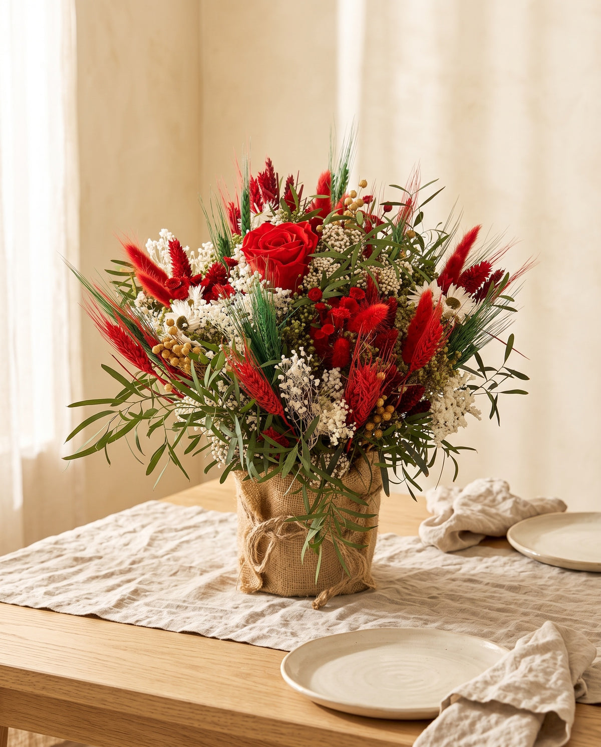 Centro de flores secas y preservadas en rojo como centro en una mesa de comedor.