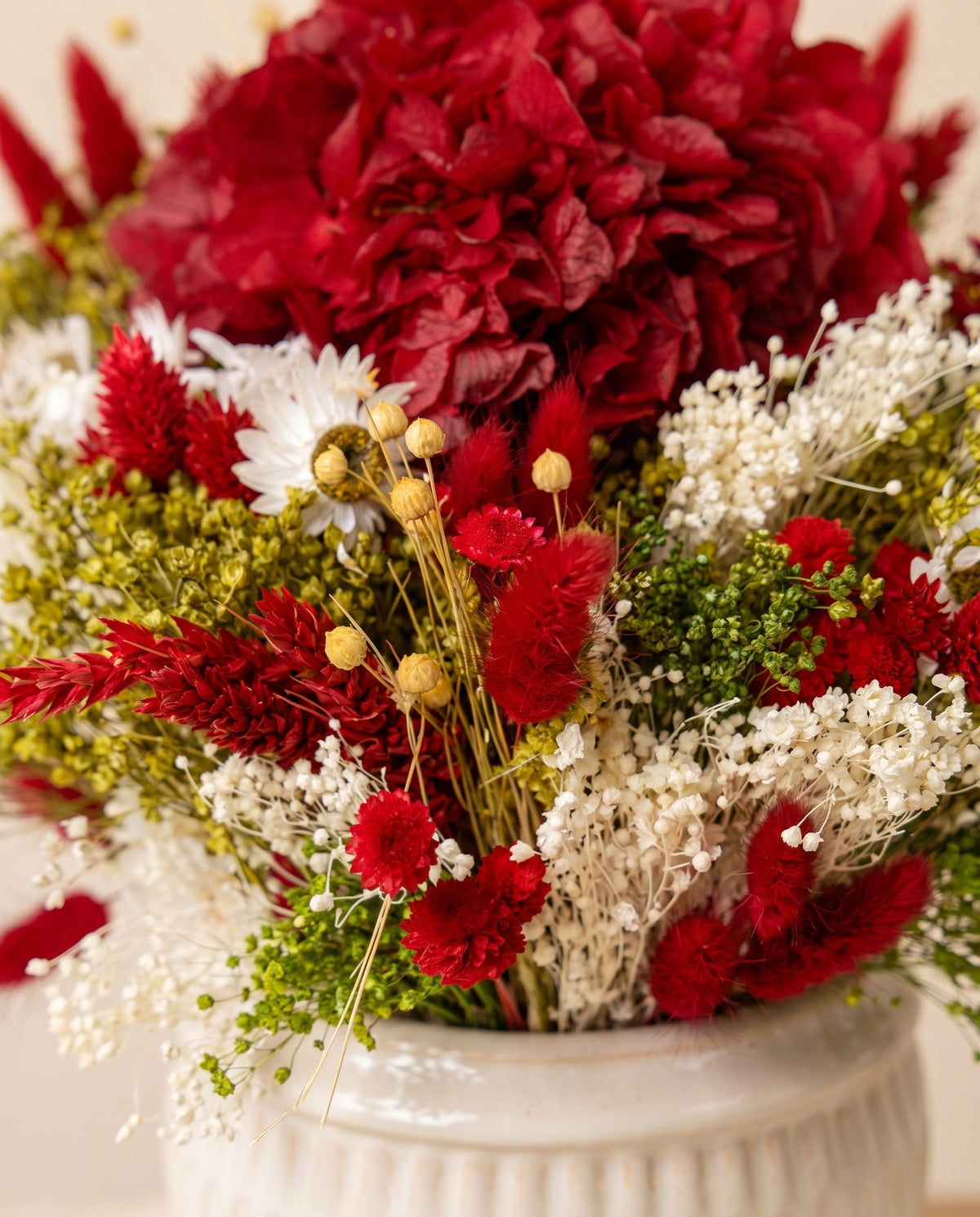 Pormenor do centro de flores secas e preservadas em vermelho e branco.