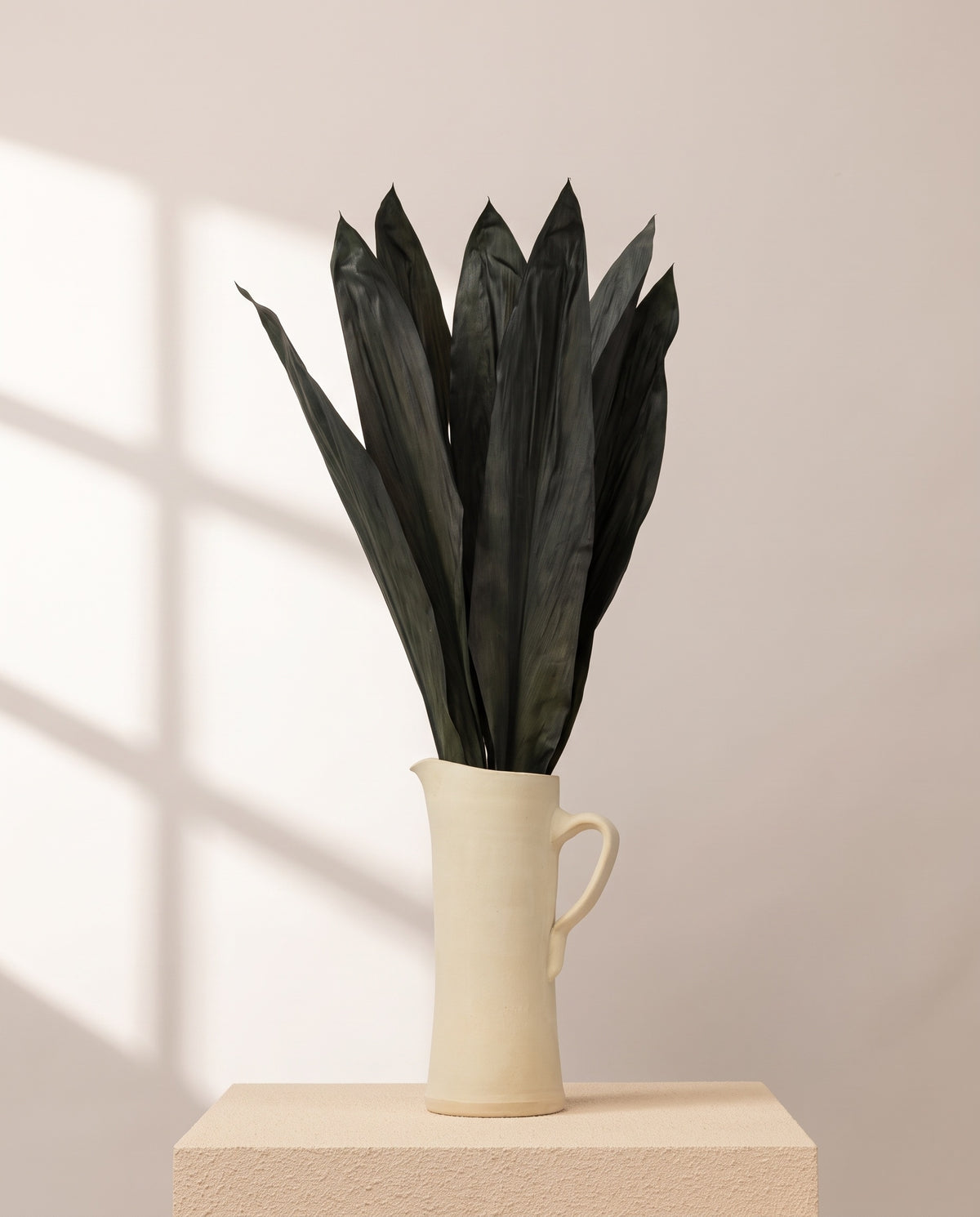 Cordyline preservada verde en una jarra de cerámica crema, ambientada. Jarra no incluida.
