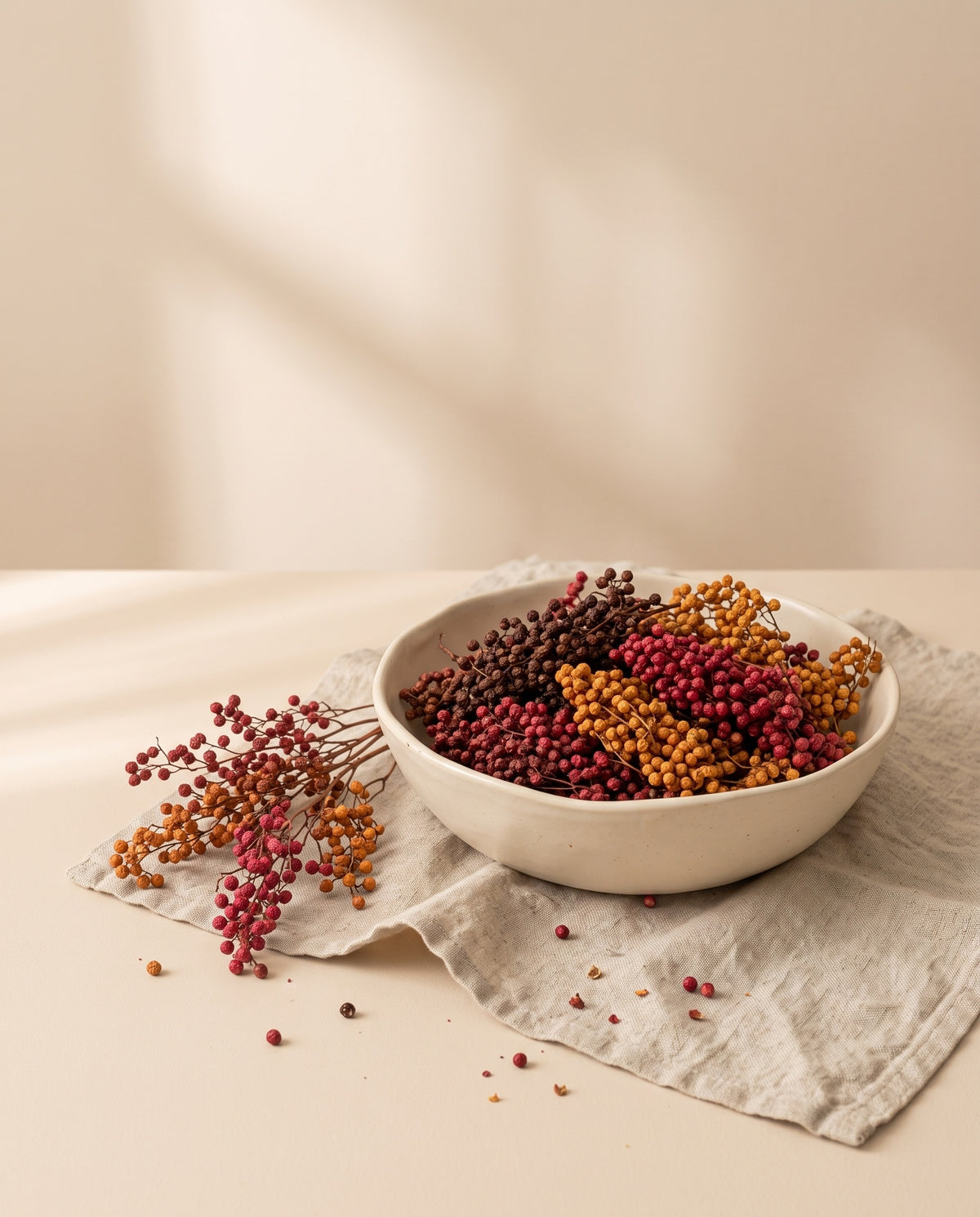 Falsa pimienta seca otoñal (rojo, burdeos y naranja) en un cuenco de cerámica. Cuenco no incluido.