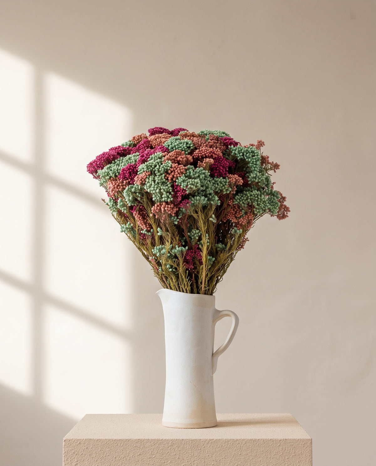 Flor-de-arroz preservada rosa-claro numa jarra de cerâmica creme. Jarra não incluída.