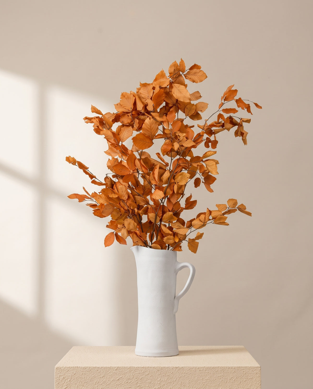 Faia preservada laranja numa jarra de cerâmica creme, em ambiente decorado. Jarra não incluída.