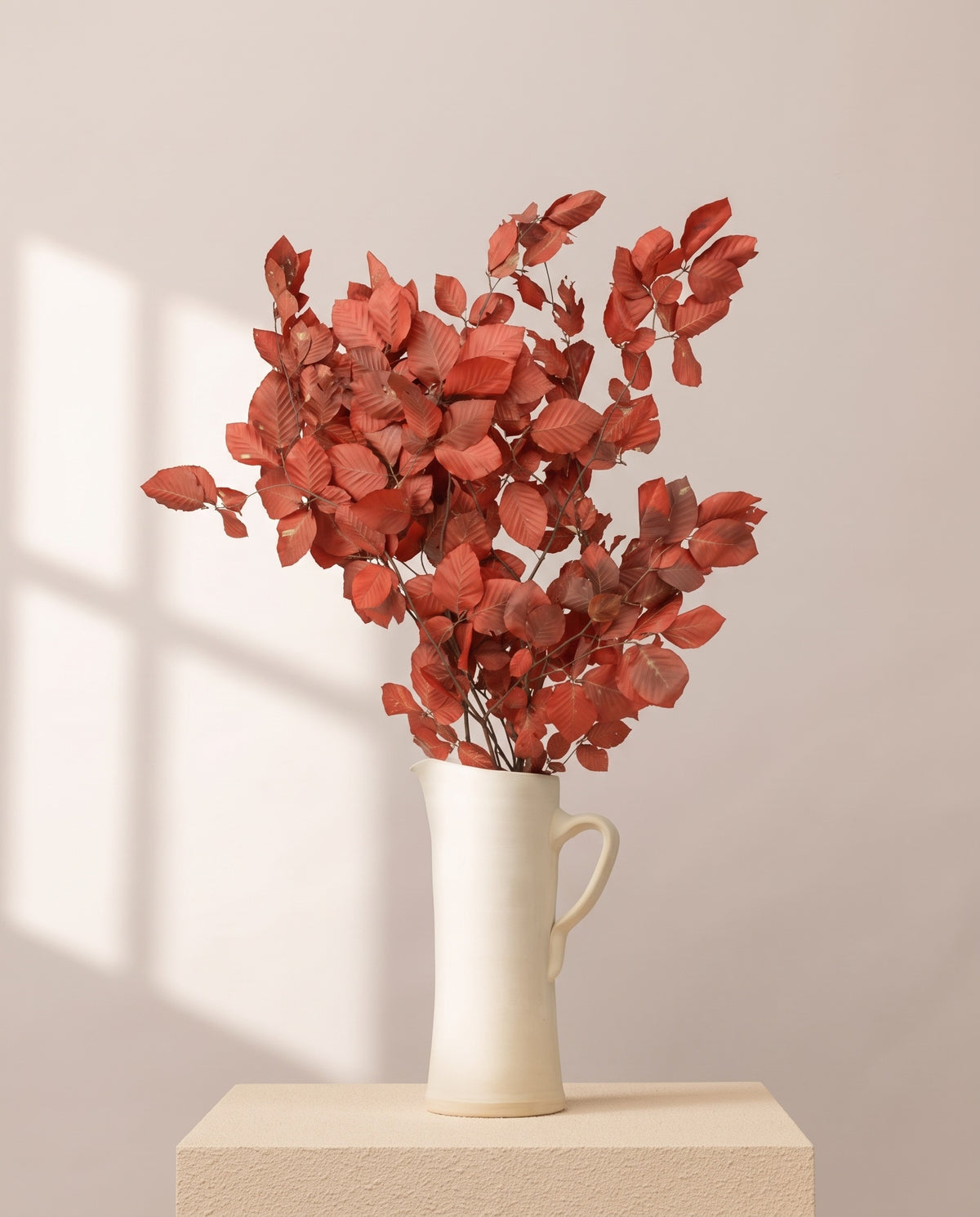 Faia preservada vermelha numa jarra de cerâmica creme, em ambiente decorado. Jarra não incluída.