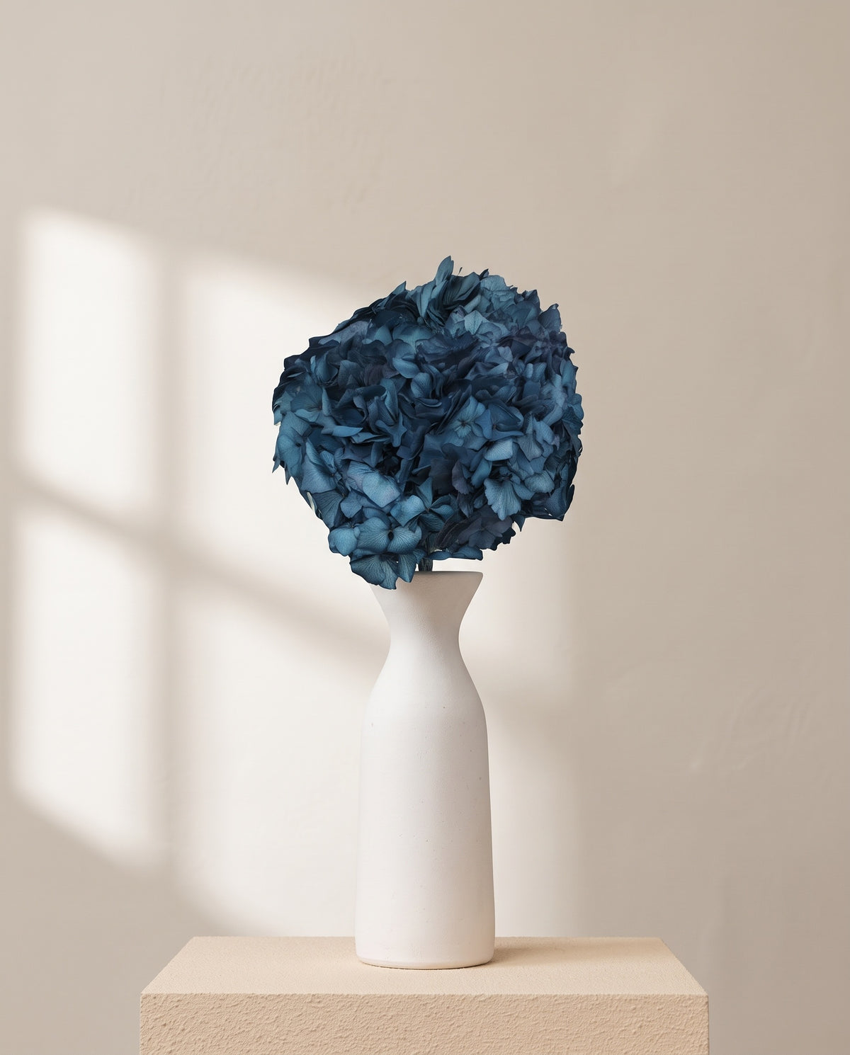 Hortensia preservada azul sobre un jarrón de cerámica blanca. Jarrón no incluido.