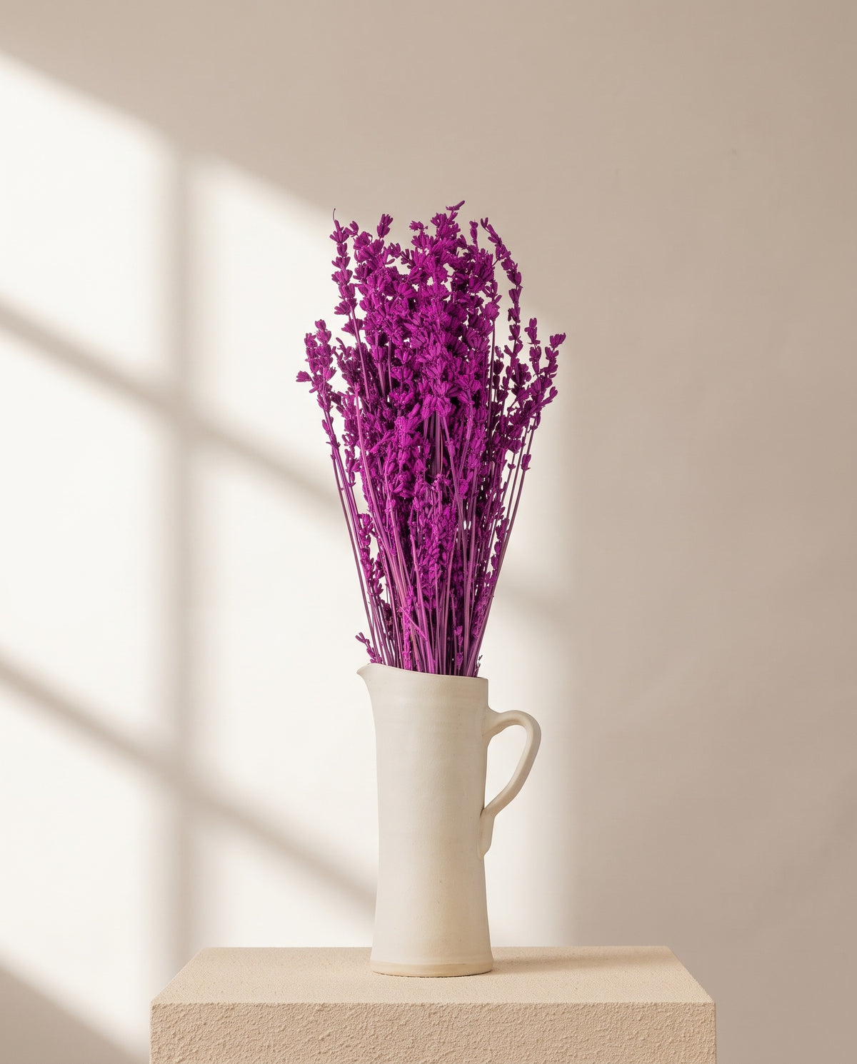 Lavanda seca fucsia en una jarra de cerámica crema. Jarra no incluida.