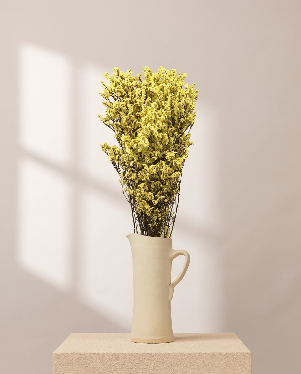 Limonium preservado amarillo en una jarra de cerámica crema. Jarra no incluida.