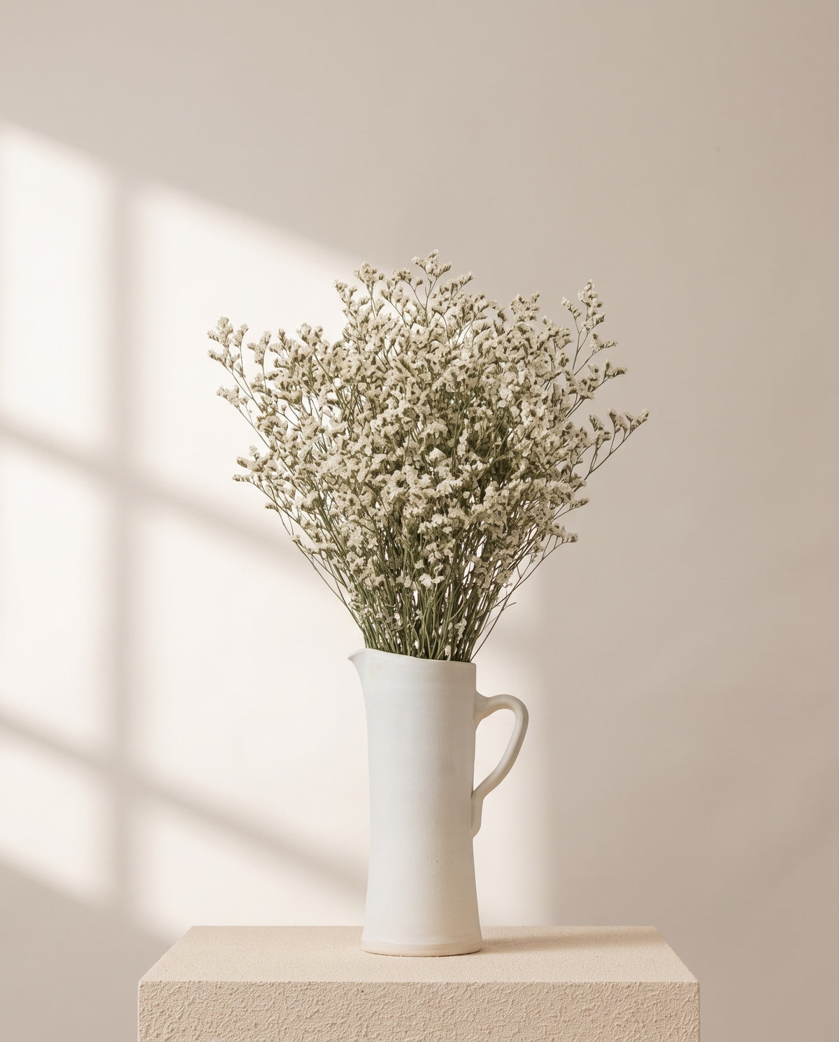 Limonium Sinensis preservado blanco en una jarra de cerámica crema. Jarra no incluida.