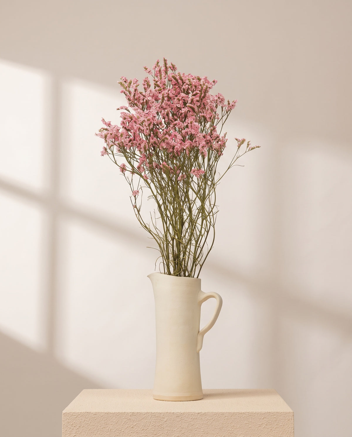 Limonium Sinensis preservado rosa en una jarra de cerámica crema. Jarra no incluida.