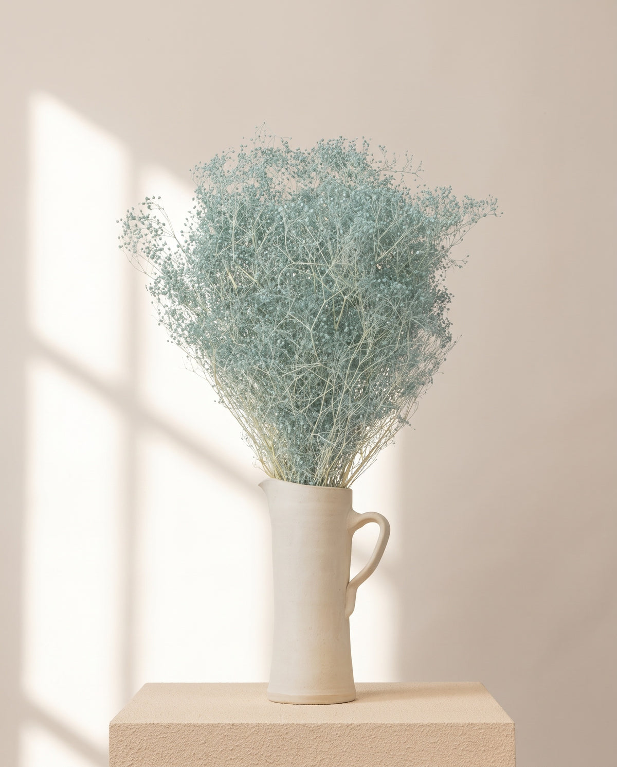 Paniculata preservada celeste en una jarra de cerámica crema. Jarra no incluida.