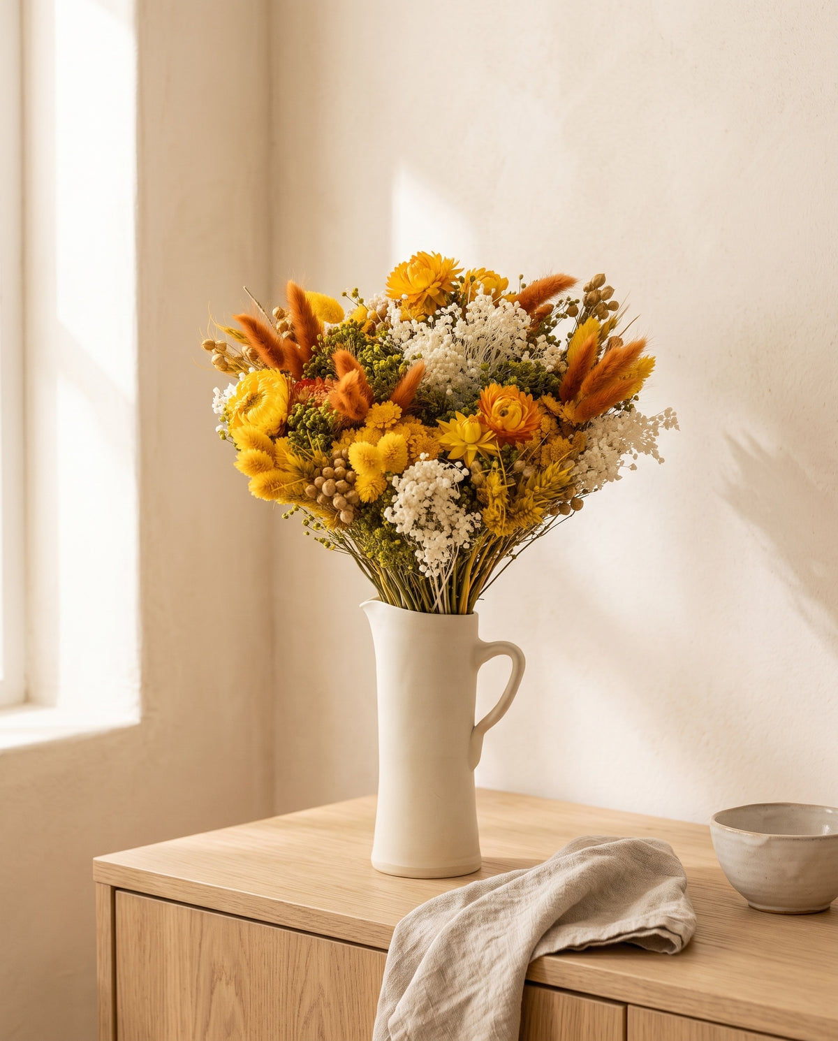 Ramo de flores secas em amarelo numa jarra sobre um aparador, ambiente de casa. Jarra não incluída.