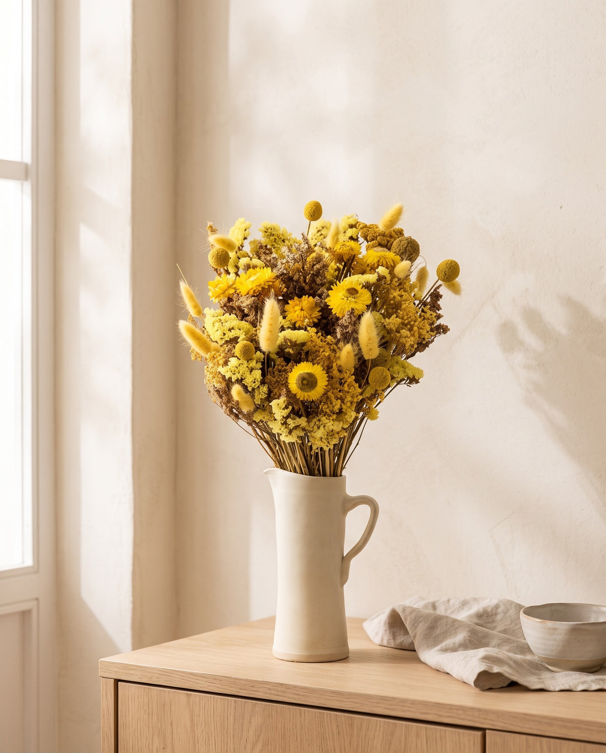 Ramo grande de flores secas em amarelo numa jarra sobre um aparador, ambiente de casa. Jarra não incluída.