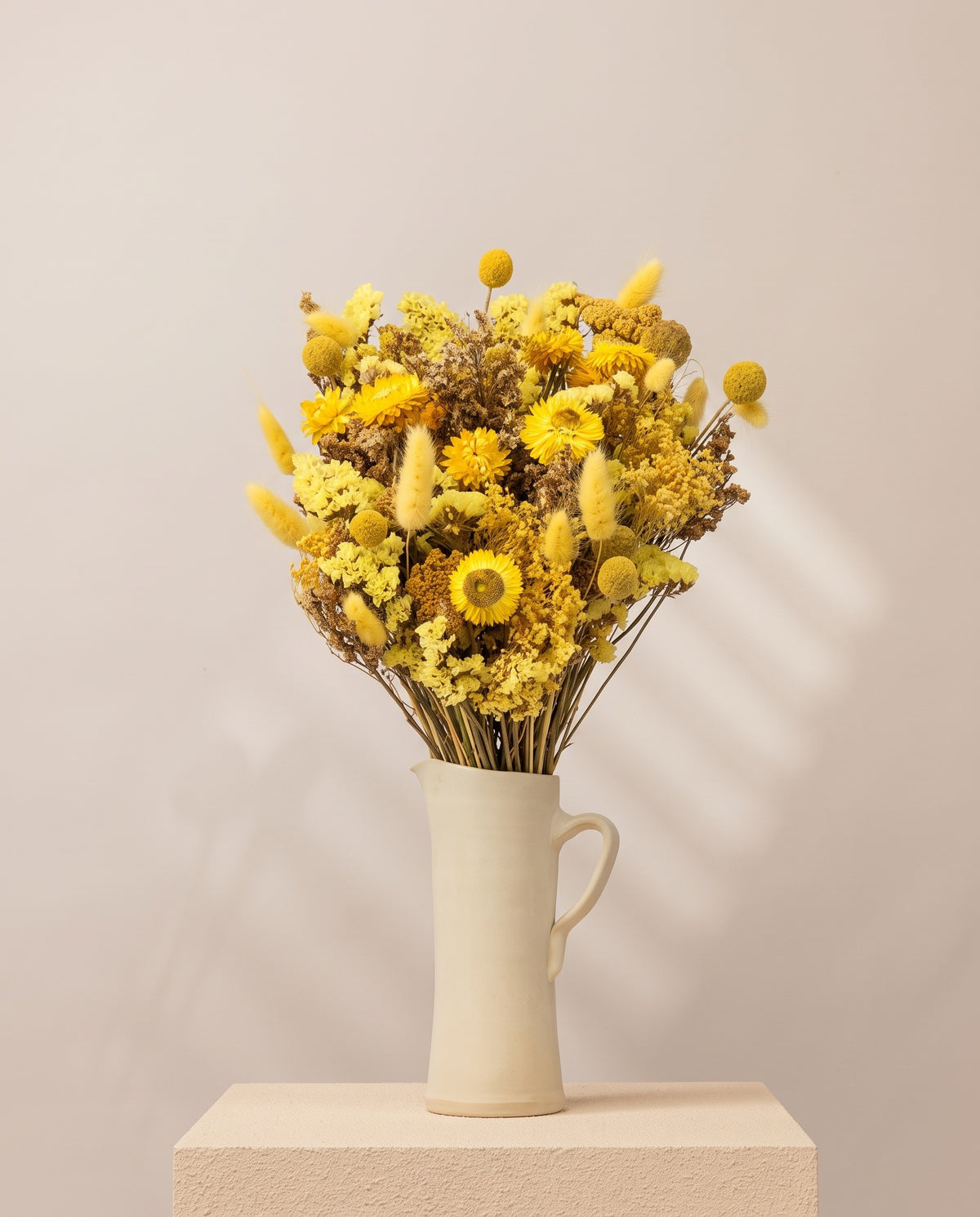 Ramo grande de flores secas en amarillo en una jarra de cerámica crema. Jarra no incluida.