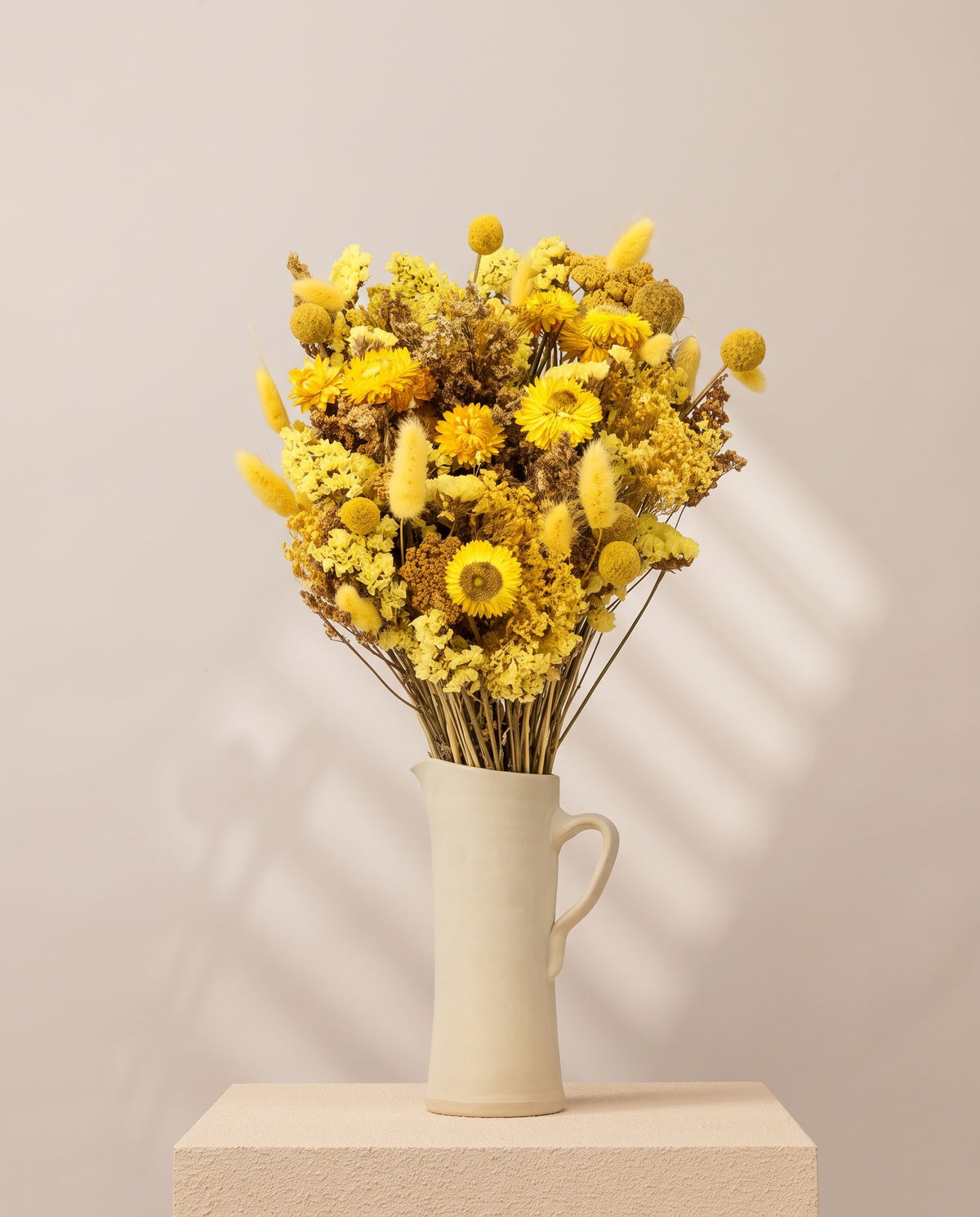 Ramo de flores secas en amarillo en una jarra de cerámica crema. Jarra no incluida.