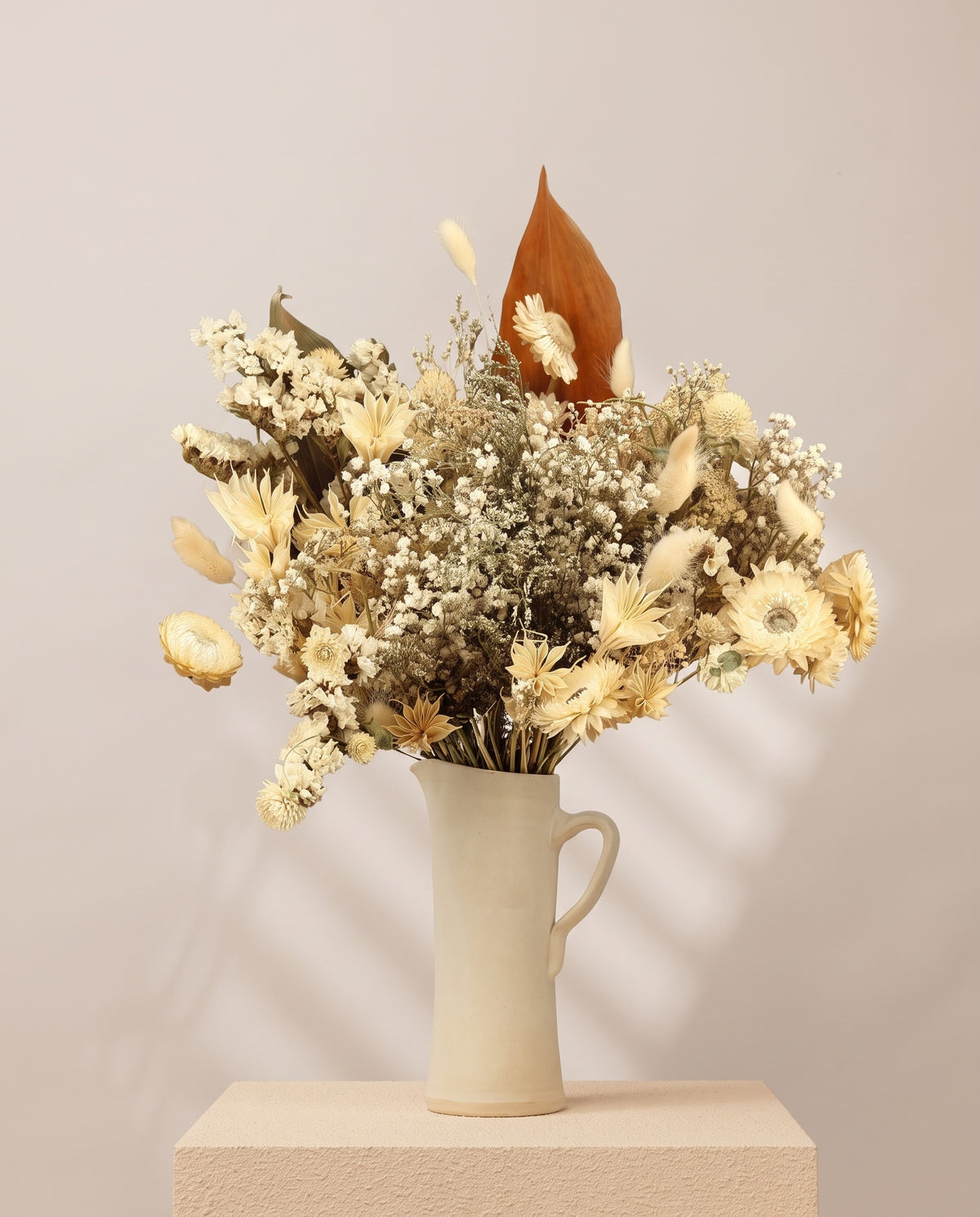 Ramo grande de flores secas em branco numa jarra de cerâmica creme. Jarra não incluída.