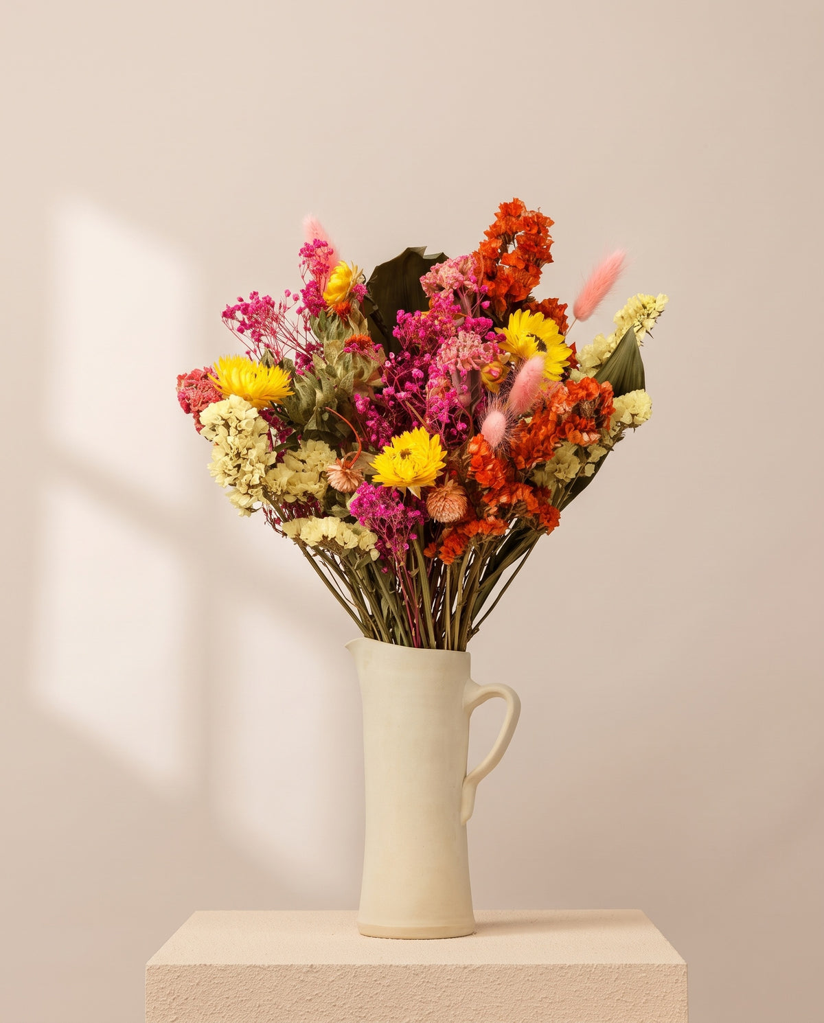 Ramo de flores secas multicolor numa jarra de cerâmica creme. Jarra não incluída.