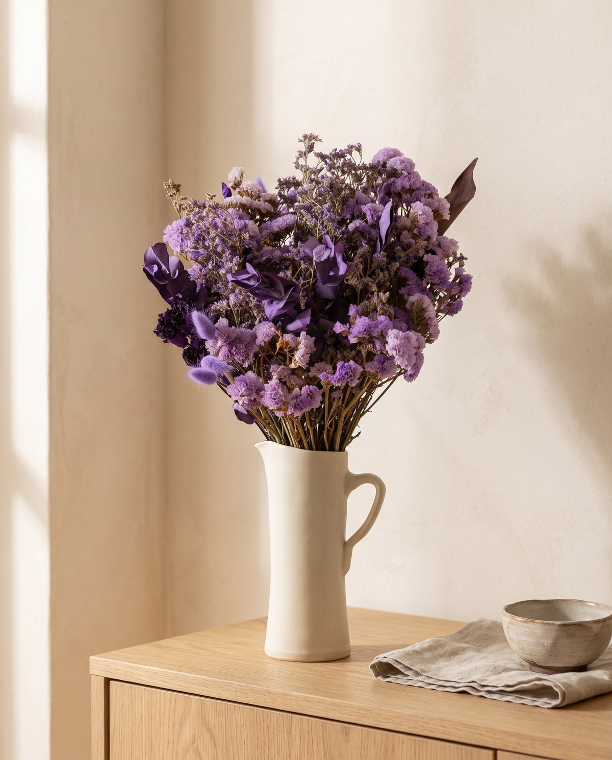 Ramo de flores secas em lavanda numa jarra sobre um aparador, ambiente de casa. Jarra não incluída.