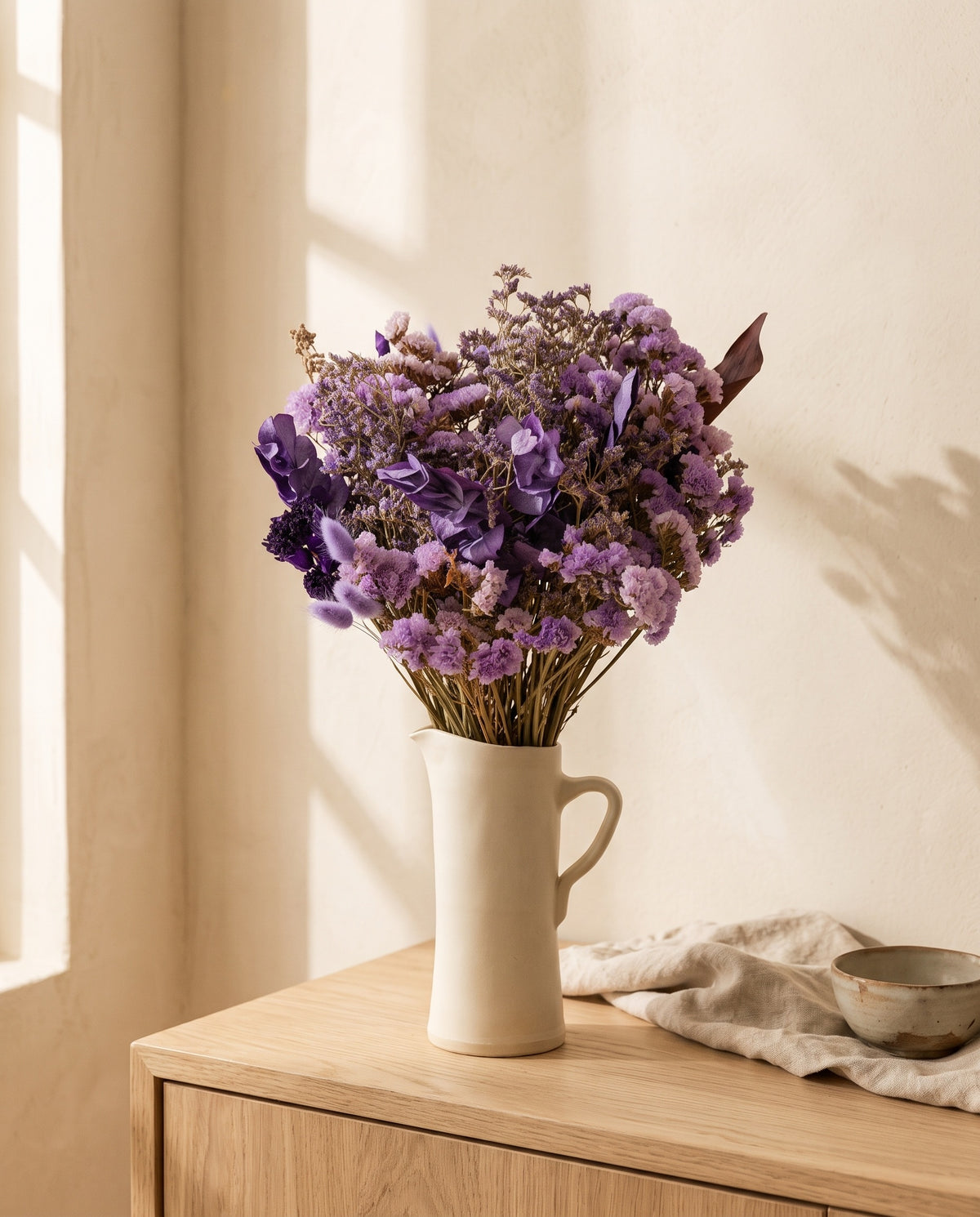 Ramo grande de flores secas em lavanda numa jarra sobre um aparador, ambiente de casa. Jarra não incluída.