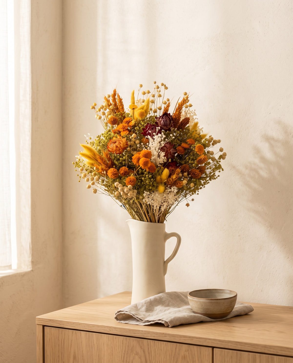 Ramo de flores secas em laranja com helichrysum numa jarra sobre um aparador, ambiente de casa. Jarra não incluída.