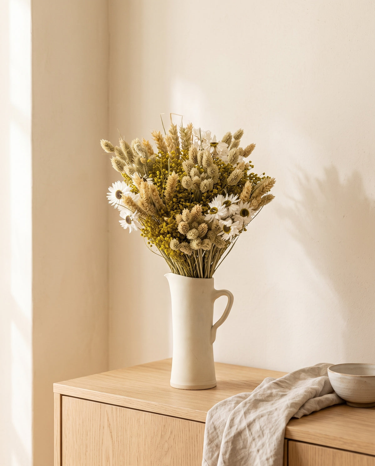 Ramo de flores secas em tons naturais com phalaris numa jarra sobre um aparador, ambiente de casa. Jarra não incluída.