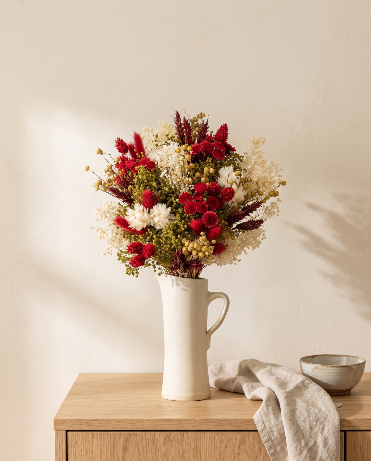 Ramo de flores secas em vermelho numa jarra sobre um aparador, ambiente de casa. Jarra não incluída.