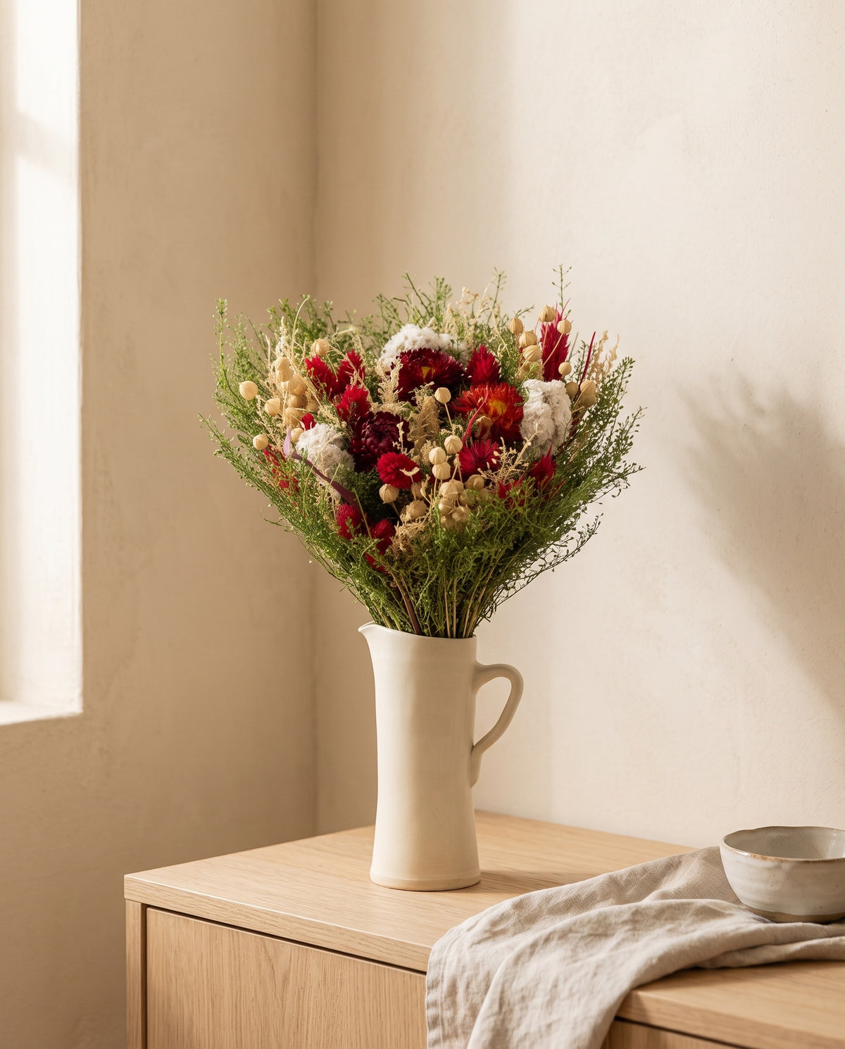 Ramo de flores secas em vermelho numa jarra sobre um aparador, ambiente de casa. Jarra não incluída.