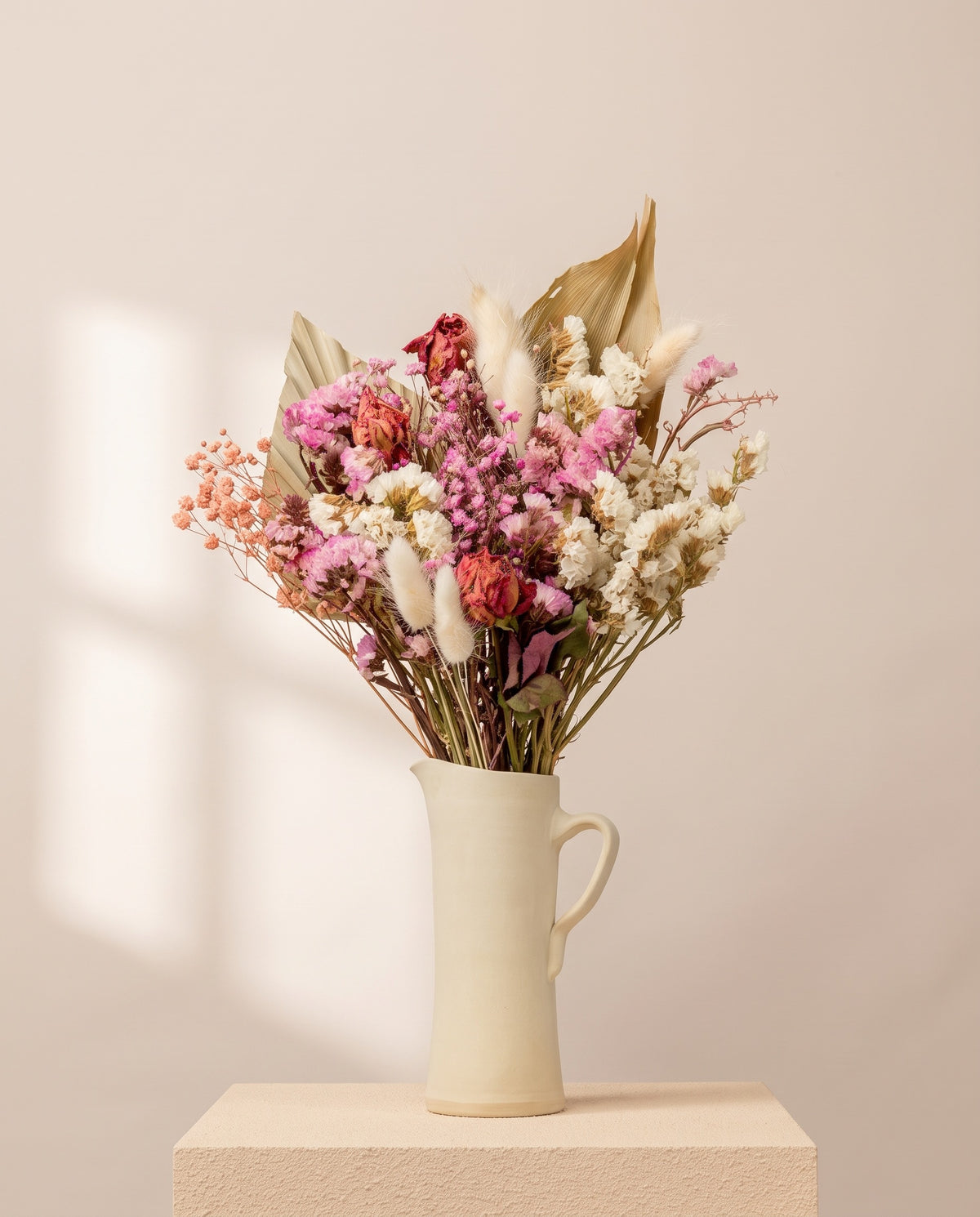 Ramo de flores secas em rosa numa jarra de cerâmica creme. Jarra não incluída.