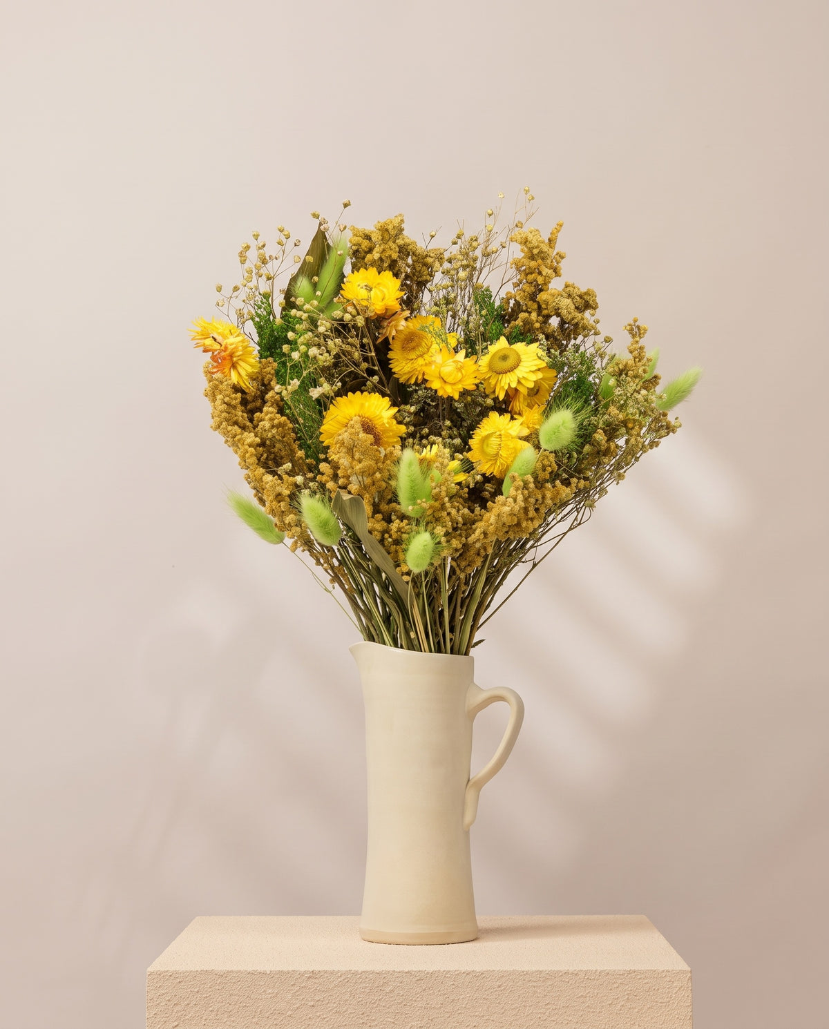 Ramo grande de flores secas em verde e amarelo numa jarra de cerâmica creme. Jarra não incluída.