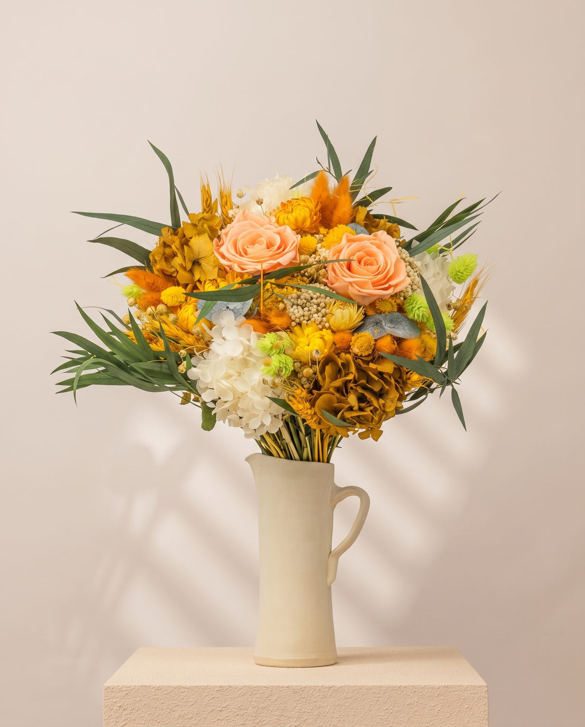 Ramo de flores secas y preservadas en amarillo en una jarra de cerámica crema. Jarra no incluida.