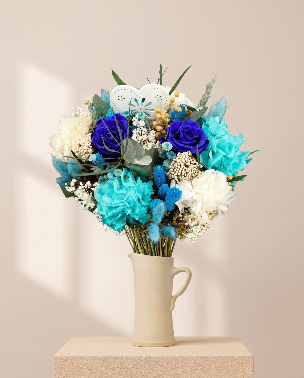 Ramo de flores secas y preservadas en azul en una jarra de cerámica crema. Jarra no incluida.