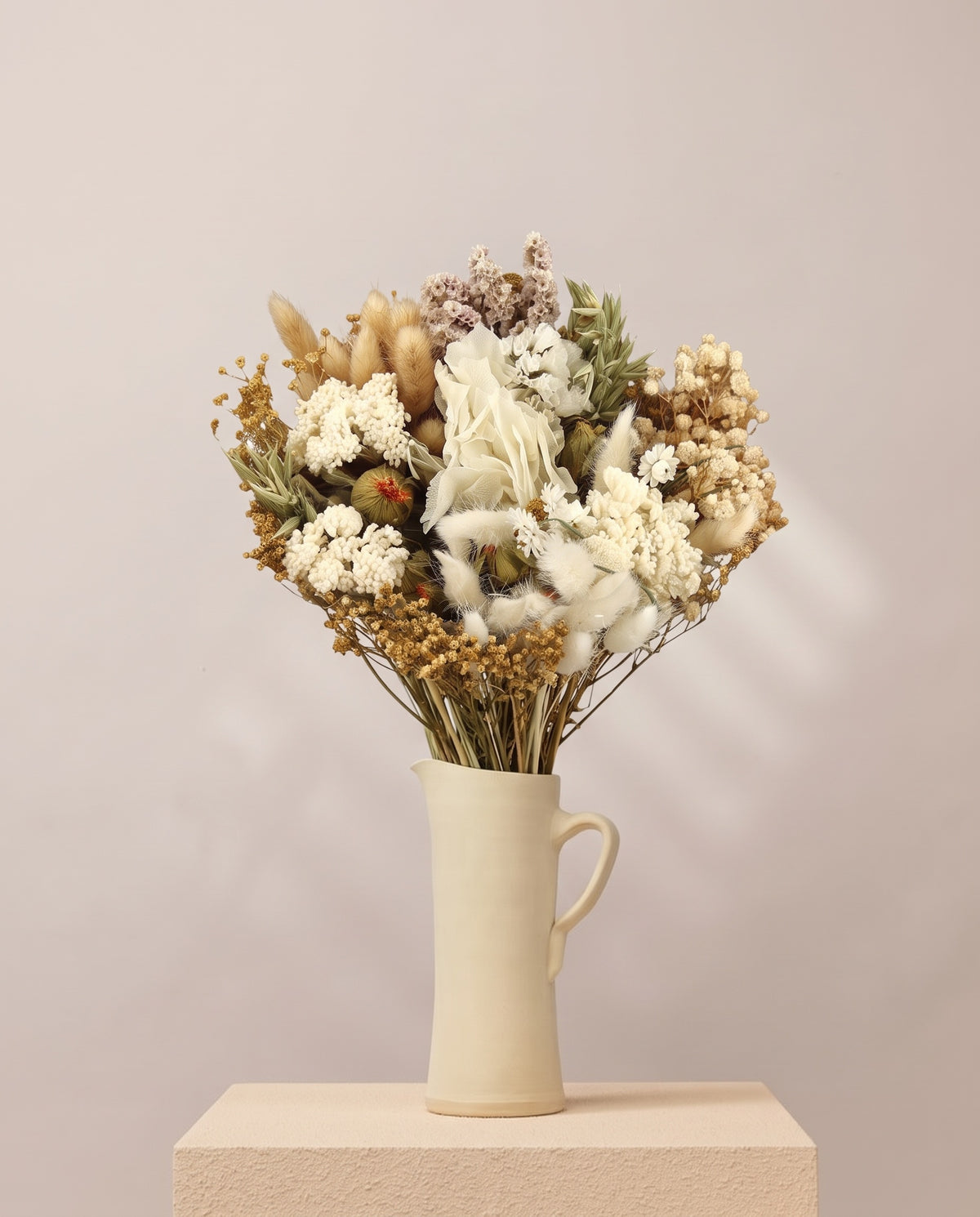 Ramo de flores secas y preservadas en blanco con lagurus en una jarra de cerámica crema. Jarra no incluida.
