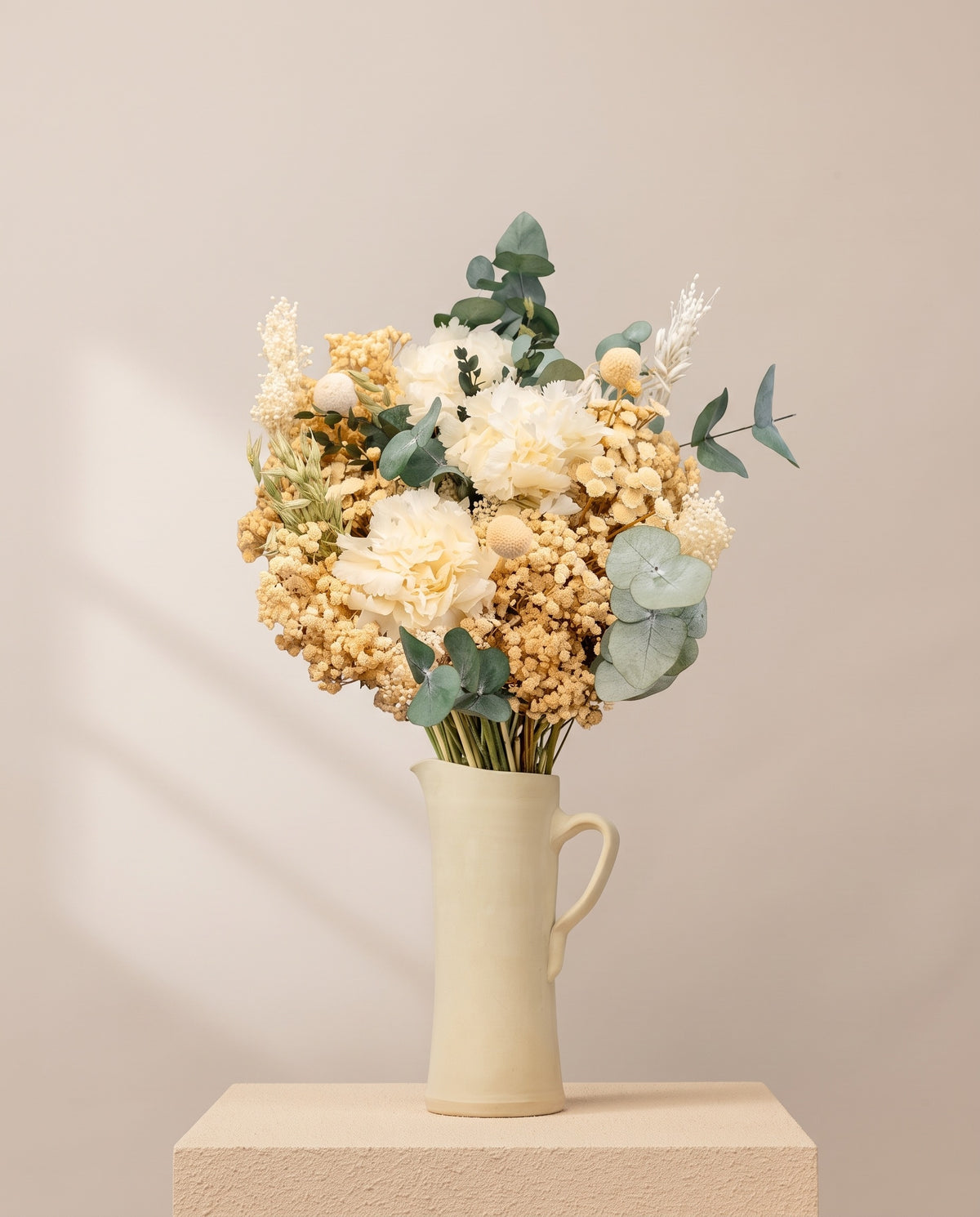 Ramo de flores secas y preservadas en blanco en una jarra de cerámica crema. Jarra no incluida.