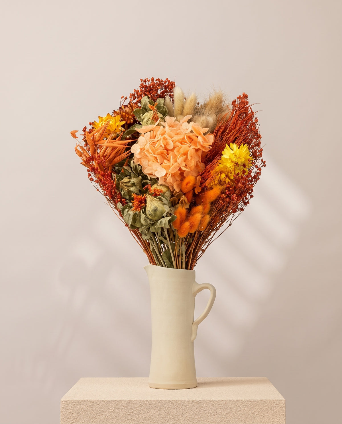 Ramo de flores secas y preservadas en naranja con hortensia en una jarra de cerámica crema. Jarra no incluida.