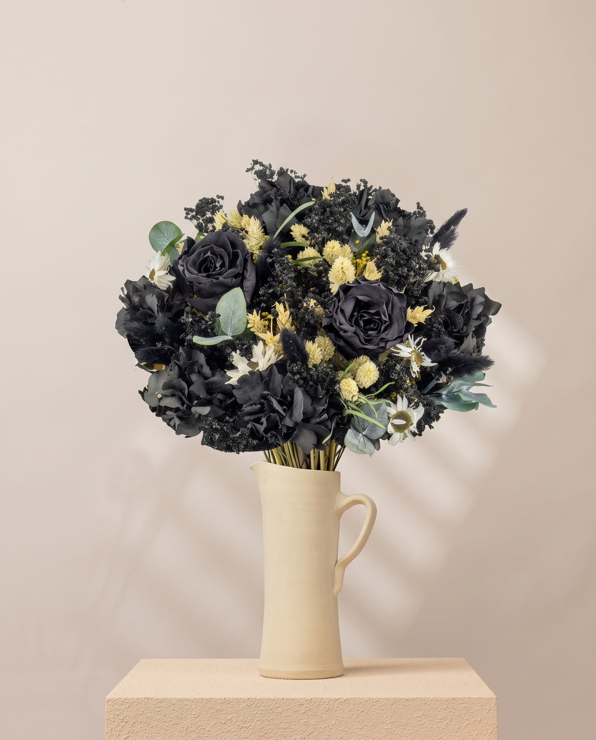 Ramo de flores secas y preservadas en negro en una jarra de cerámica crema. Jarra no incluida.