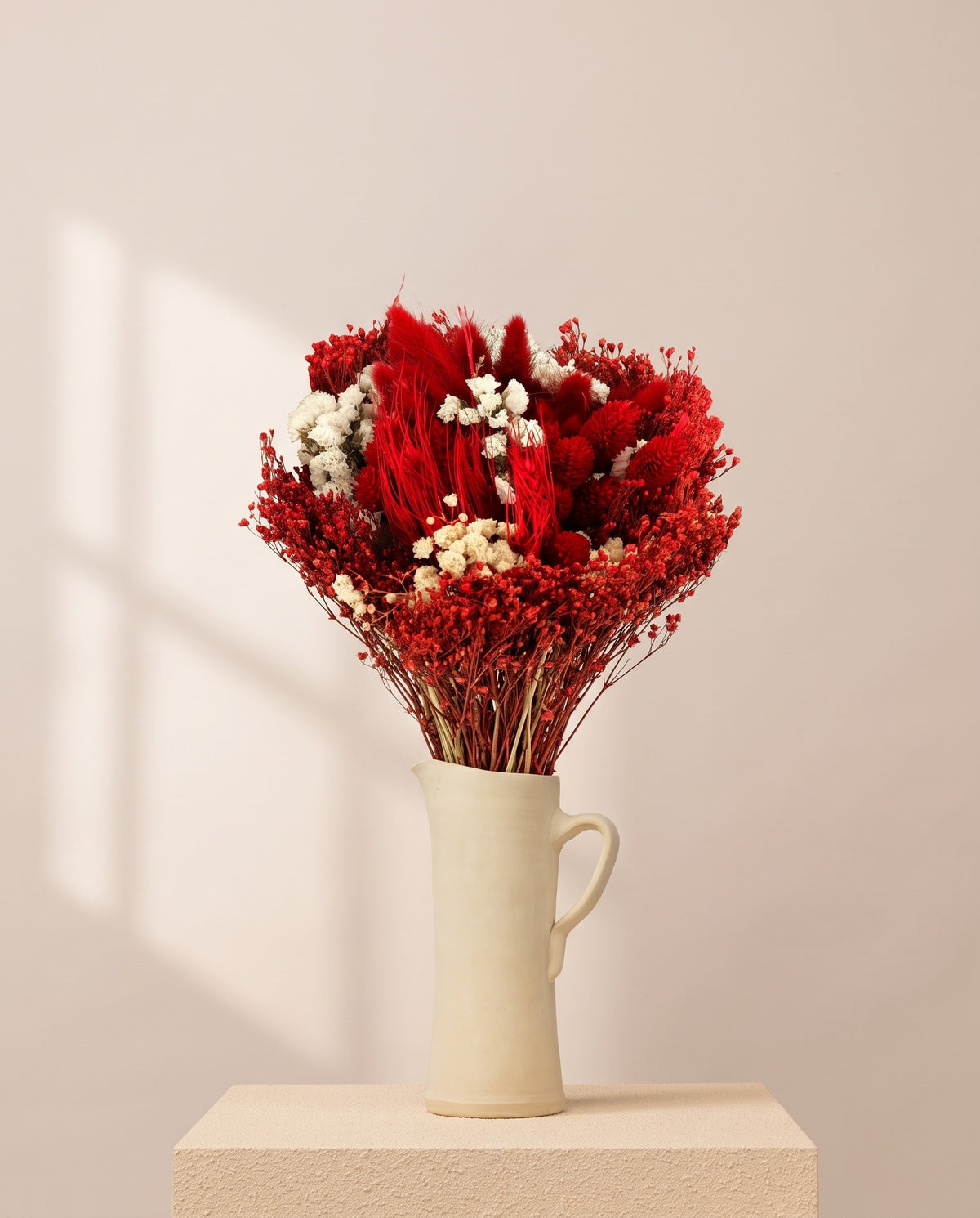 Ramo de flores secas y preservadas en rojo con lagurus en una jarra de cerámica crema. Jarra no incluida.