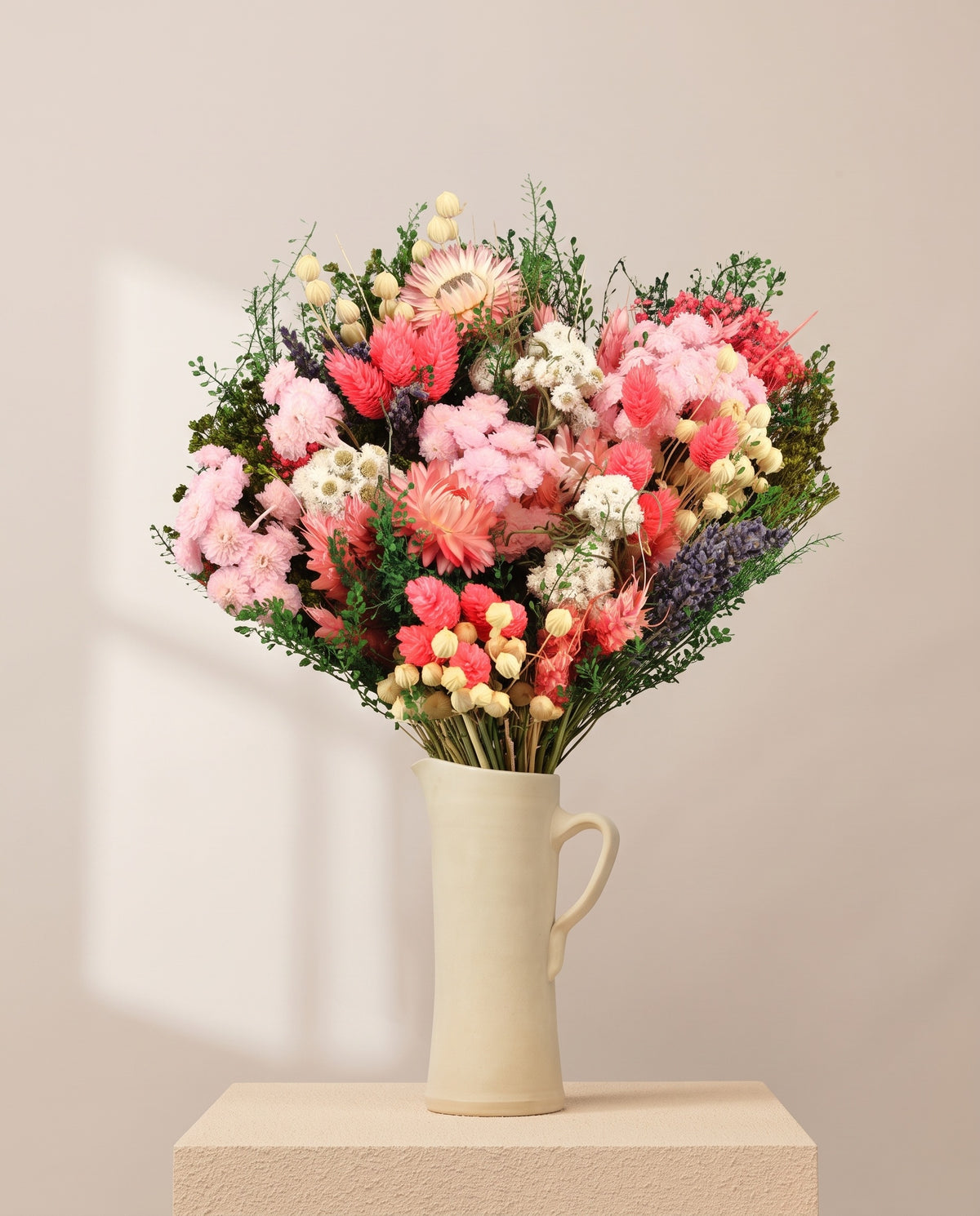 Ramo de flores secas y preservadas en rosa en una jarra de cerámica crema. Jarra no incluida.