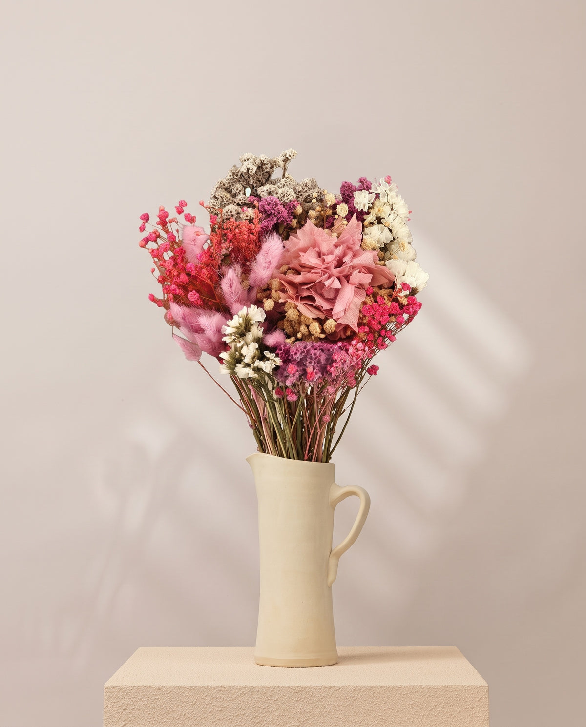 Ramo de flores secas y preservadas en rosa con hortensia en una jarra de cerámica crema. Jarra no incluida.