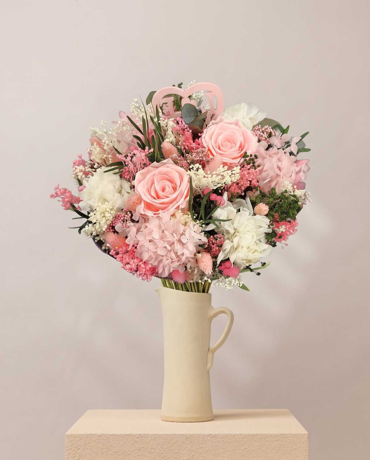 Ramo de flores secas y preservadas en rosa con rosas en una jarra de cerámica crema. Jarra no incluida.
