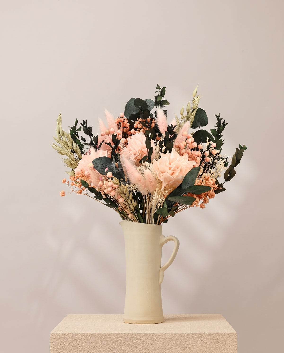Ramo de flores secas y preservadas en rosa claro en una jarra de cerámica crema. Jarra no incluida.