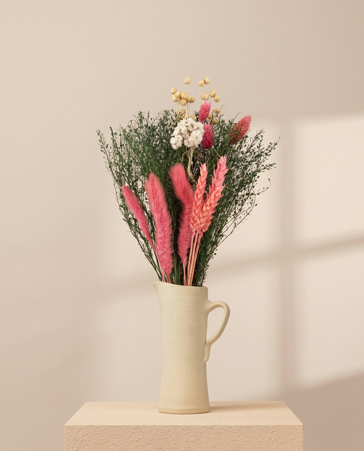 Ramo mini de flores secas cor-de-rosa numa jarra de cerâmica creme. Jarra não incluída.