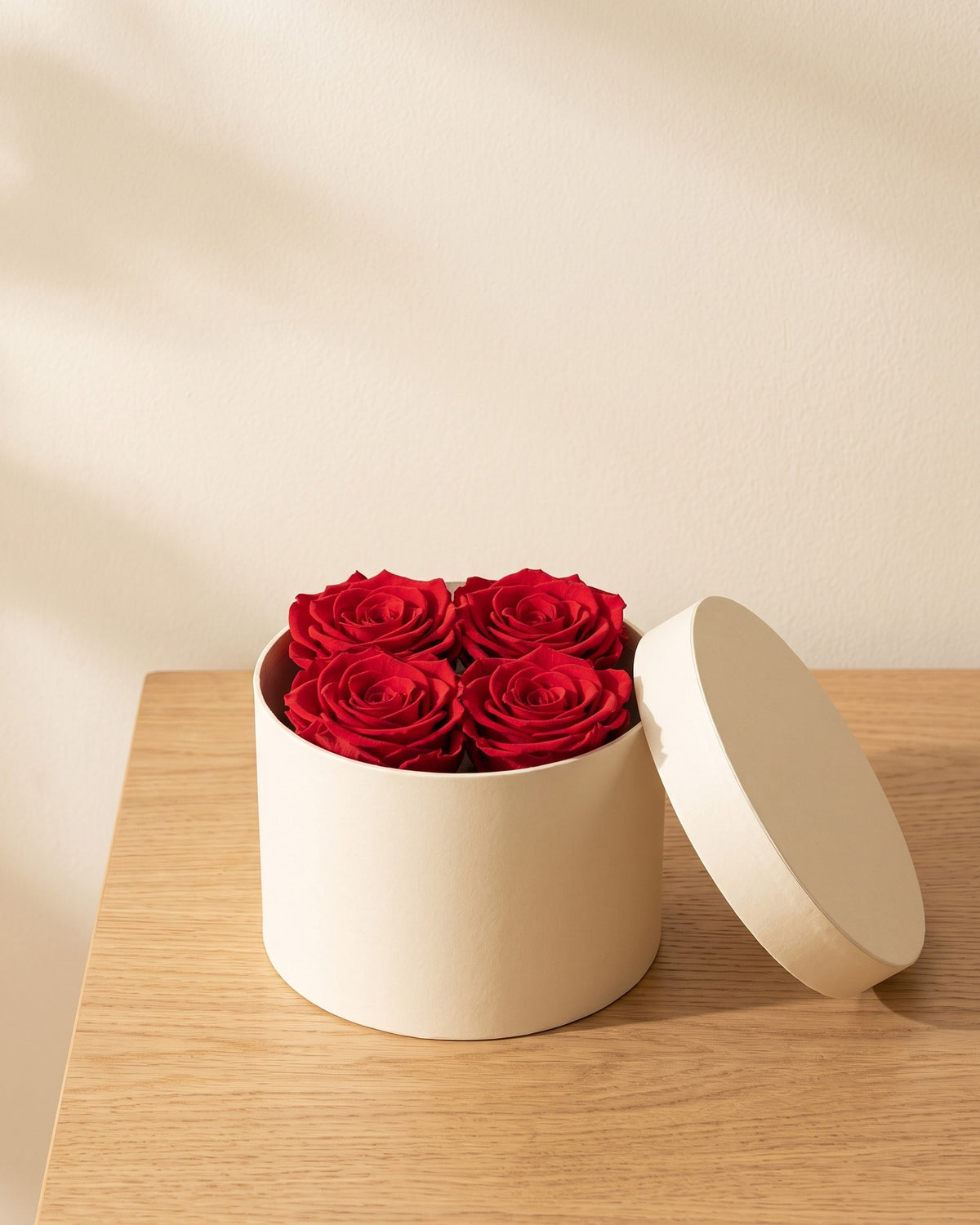 Cabeças de rosa preservada vermelha numa caixa redonda de oferta, em ambiente decorado. Caixa de oferta não incluída.