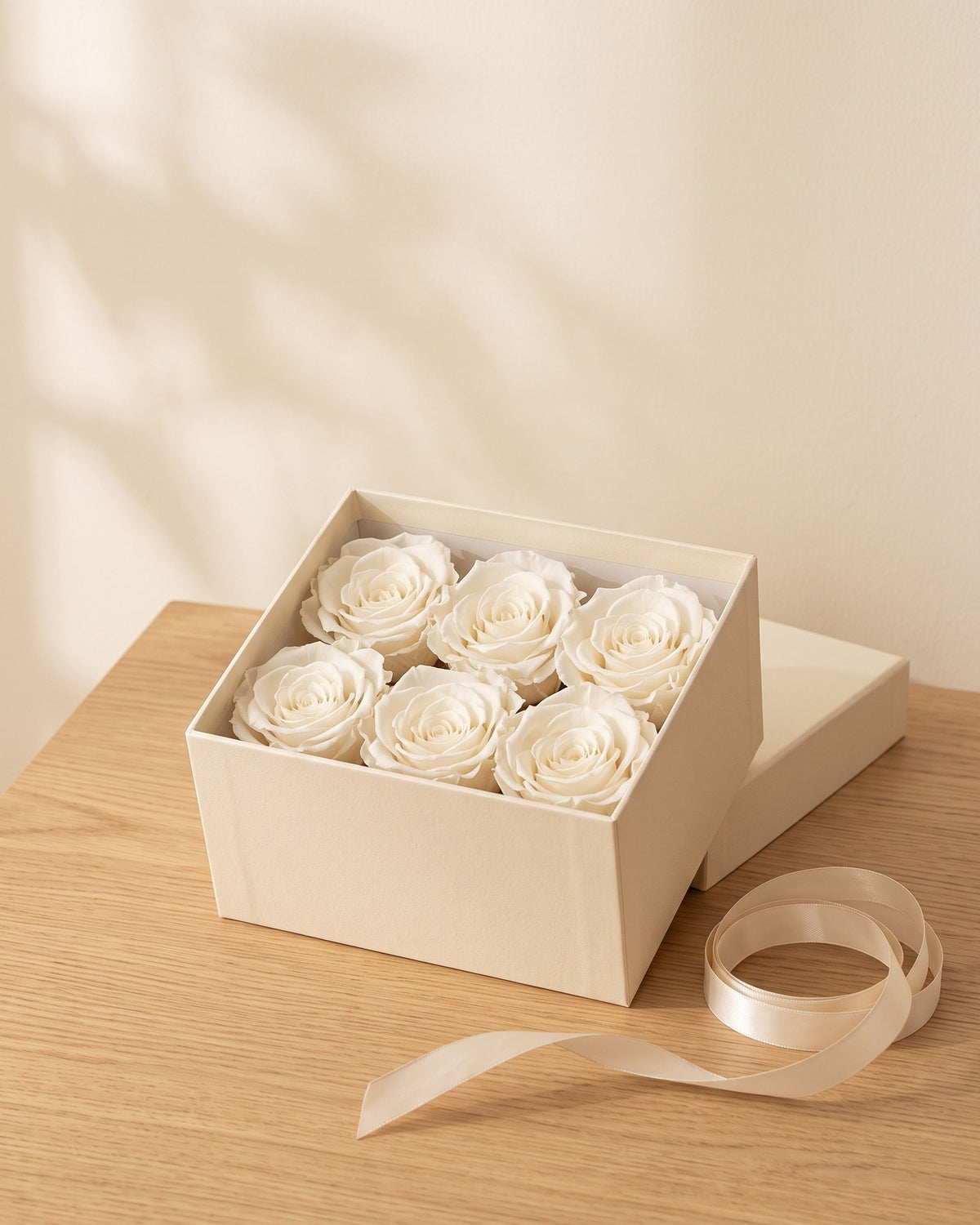 Cabezas de rosa preservada blanca en una caja de regalo, ambientada. Caja de regalo no incluida.