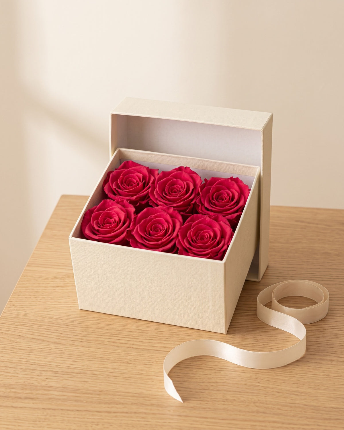 Cabezas de rosa preservada fucsia en una caja de regalo, ambientada. Caja de regalo no incluida.