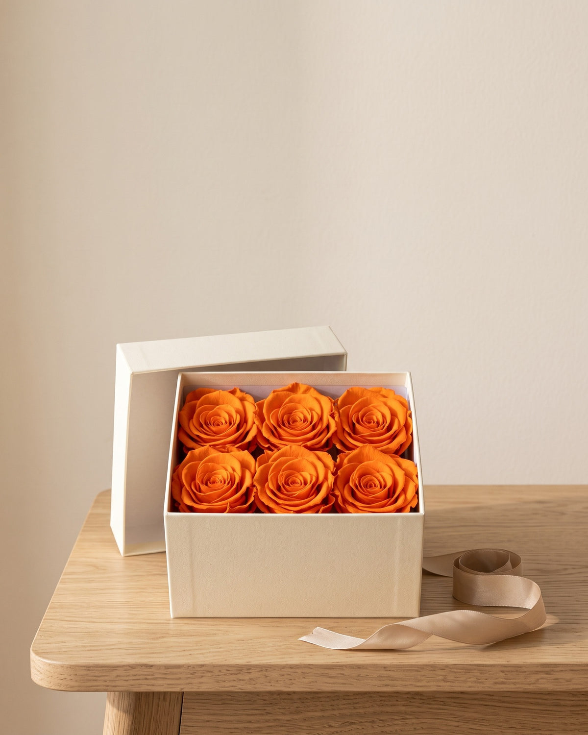 Cabezas de rosa preservada naranja en una caja de regalo, ambientada. Caja de regalo no incluida.