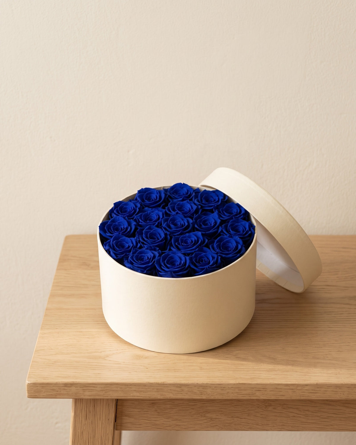 Cabezas de rosa preservada azul en una caja redonda de regalo, ambientada. Caja de regalo no incluida.